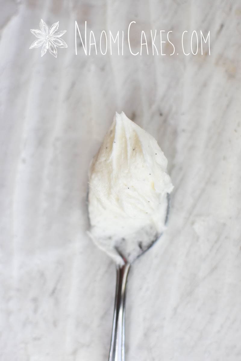 spoon with vanilla frosting on a parchment paper background
