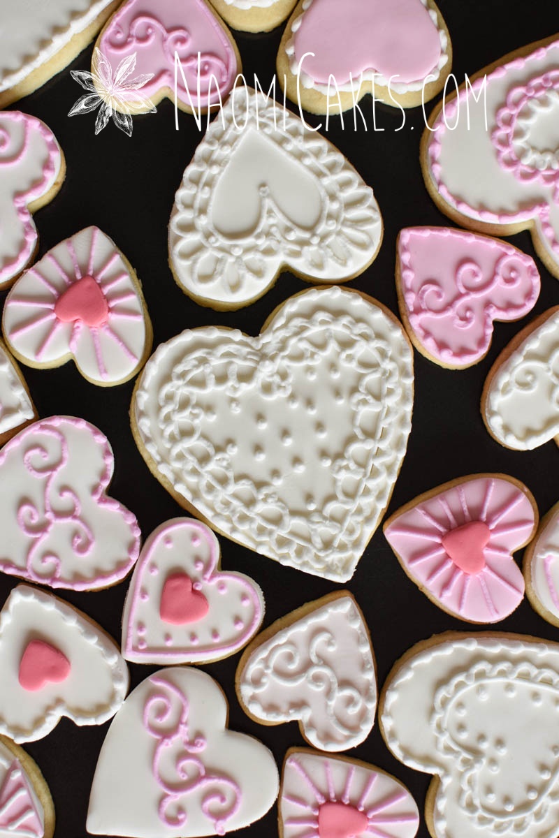 pink and white heart cookies on a black background in different sizes