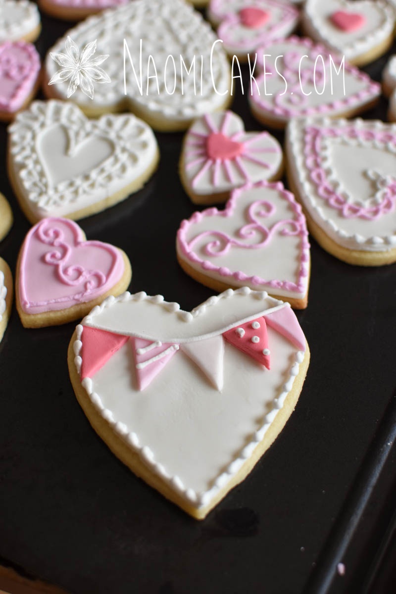 pink and white flag heart cookie on a black tray with other heart cookies in the background