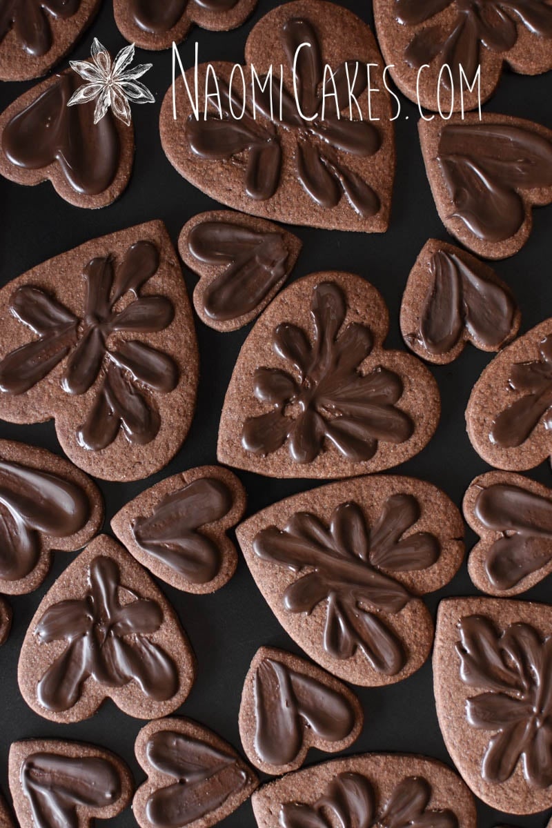 overhead view of chocolate heart shaped sugar cookies with chocolate smeared on top on a black pan