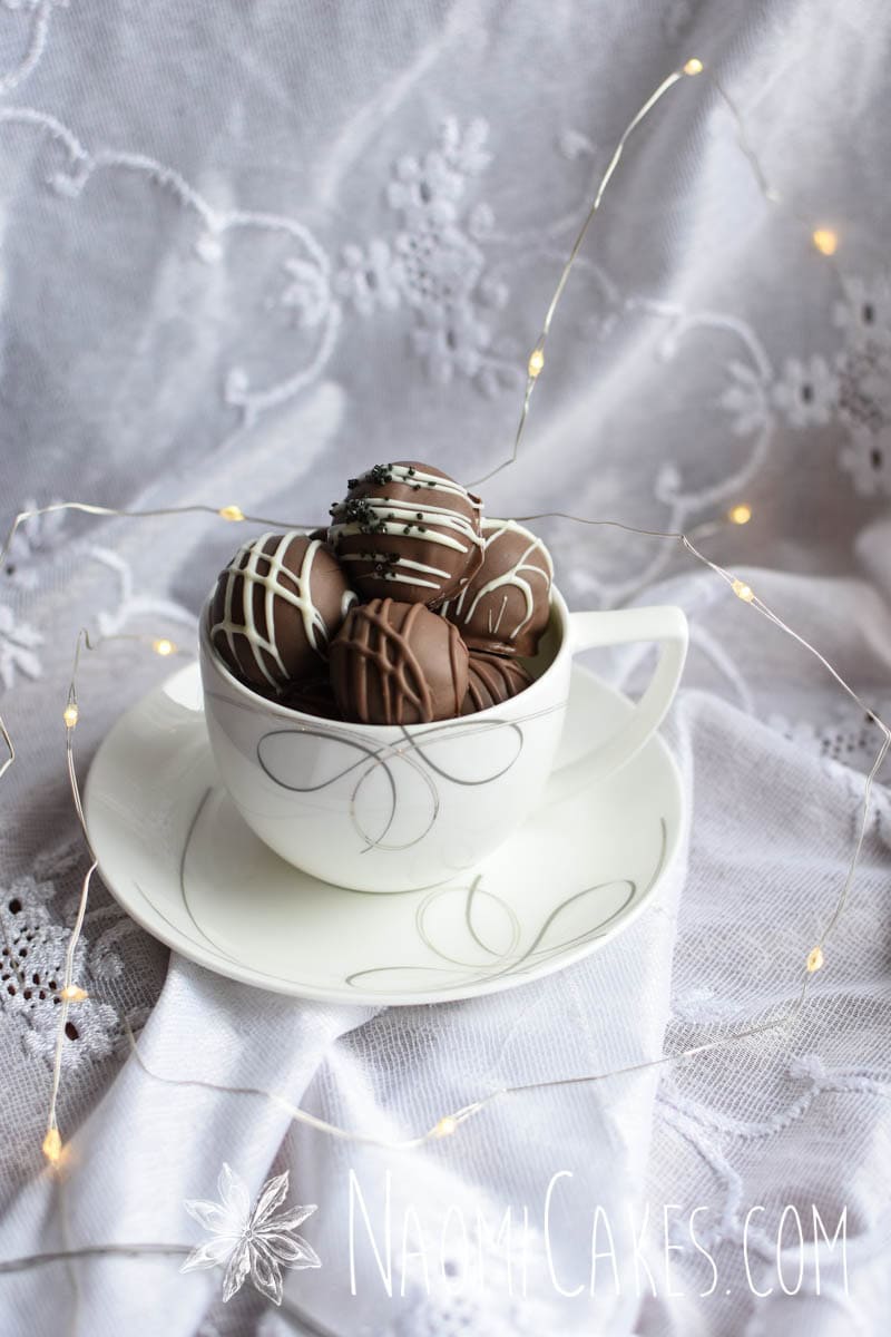 a tea cup full of chocolate truffles on lace with twinkle lights