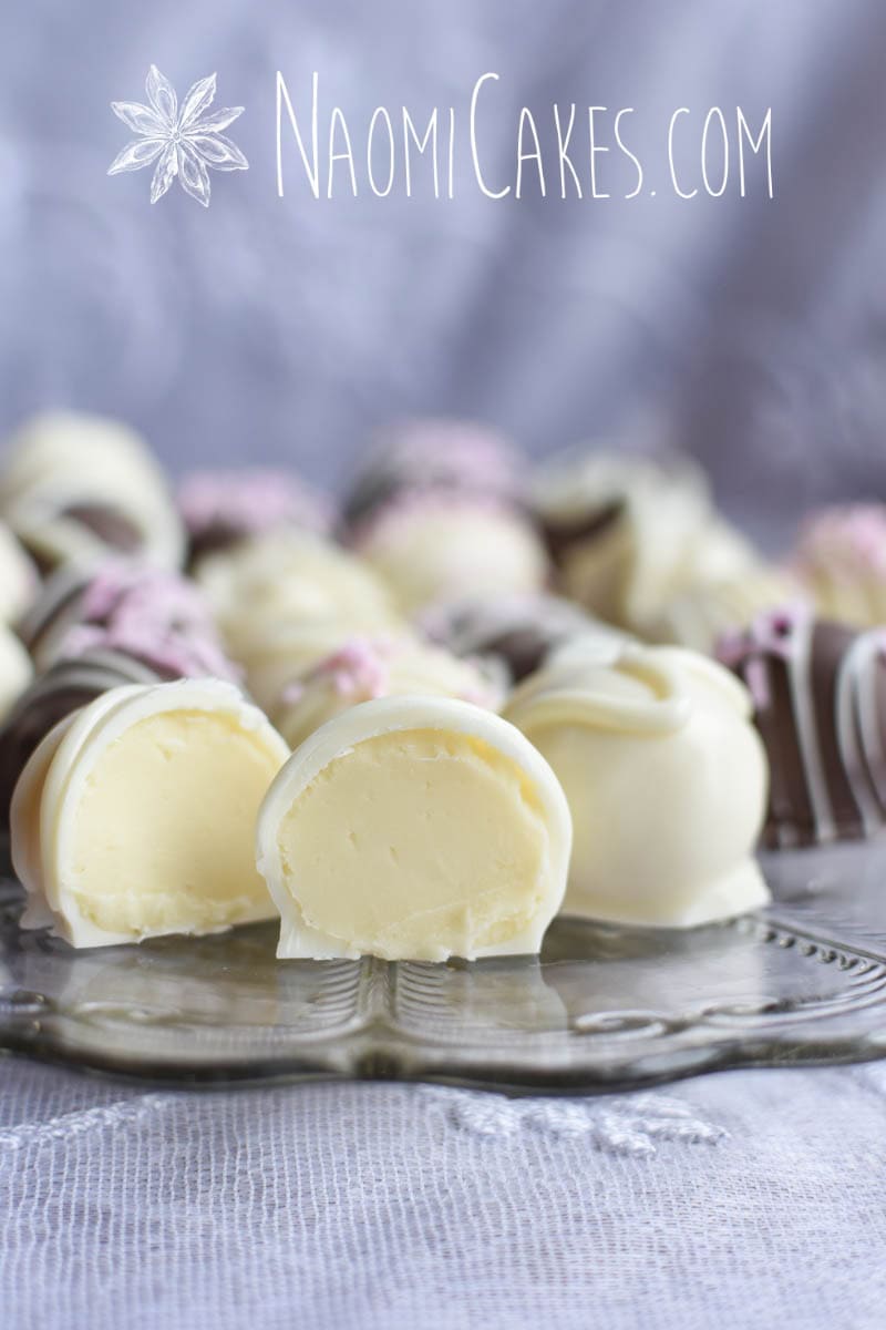 cut open white chocolate truffle on a clear glass plate with other truffles in the background