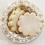 gold and white tea cup with flower shaped sugar cookies in it