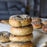 a stack of homemade sourdough everything bagels amidst other bagels on parchment