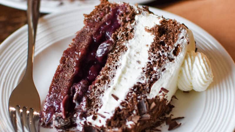 slice of German black forest cake on a white plate with a fork