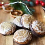 chocolate dipped lebkuchen on a cutting board with greenery and Christmas lights in the background