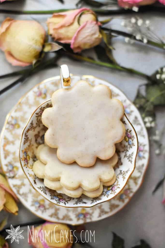 glazed cinnamon sugar cookies in a gold and white tea cup with dried roses around