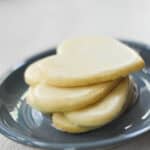 glazed heart sugar cookies on a blue plate with a white background