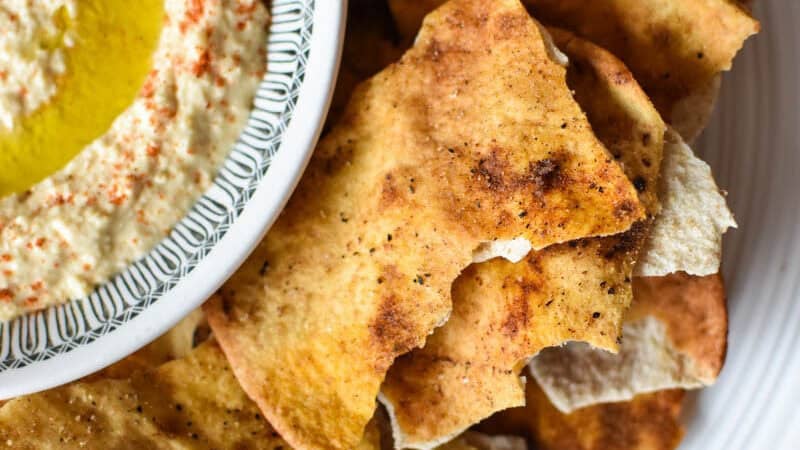close up overhead view of a large round plate with a bowl of hummus and pita chips