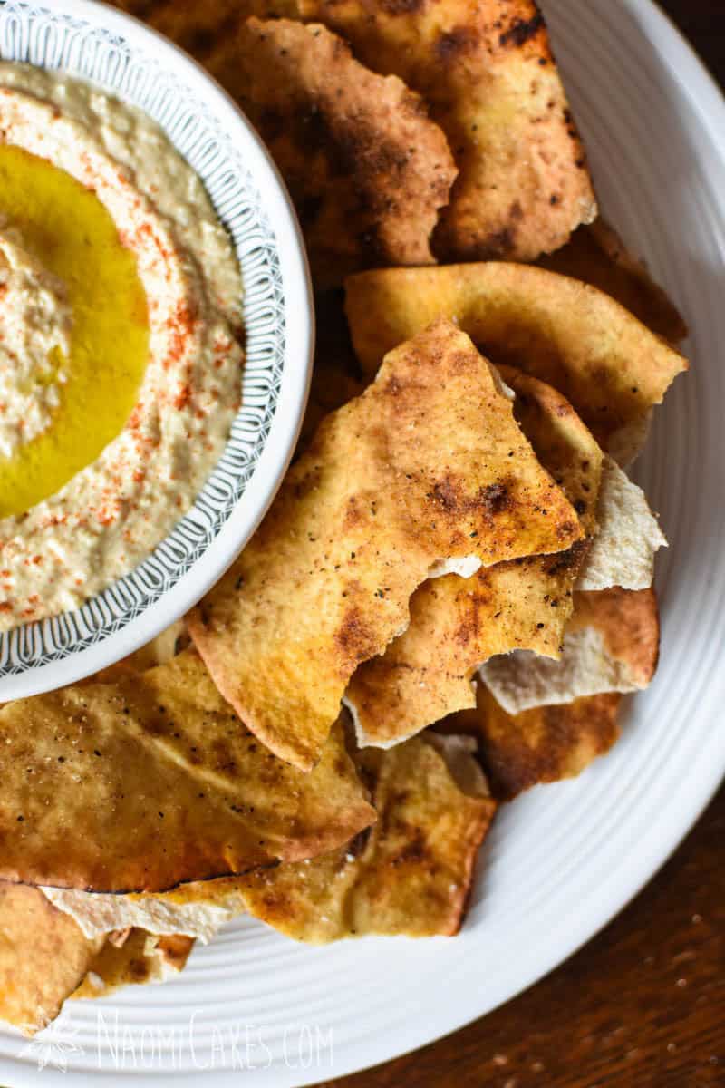 close up overhead view of a large round plate with a bowl of hummus and pita chips