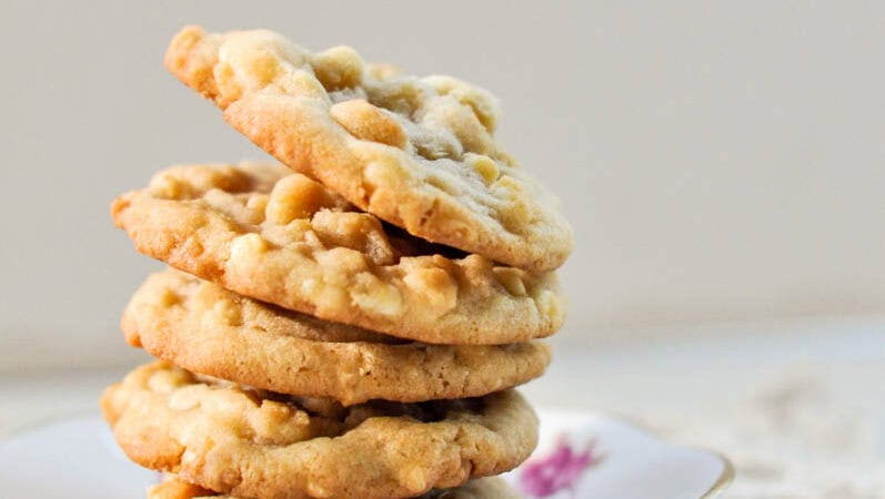 close up of white chocolate macadamia nut cookies in a stack on a tea saucer