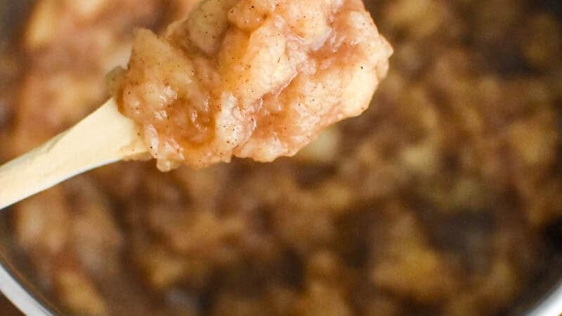 homemade large chunk applesauce in a pot with a checked cloth in the background