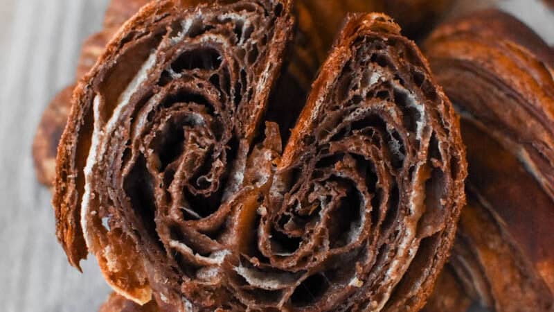 a chocolate croissant cut in half on top of other croissants
