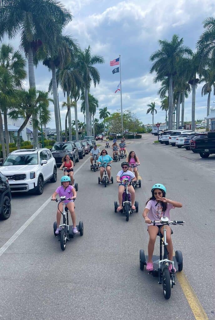 Children and adults riding electric trikes together in downtown Naples