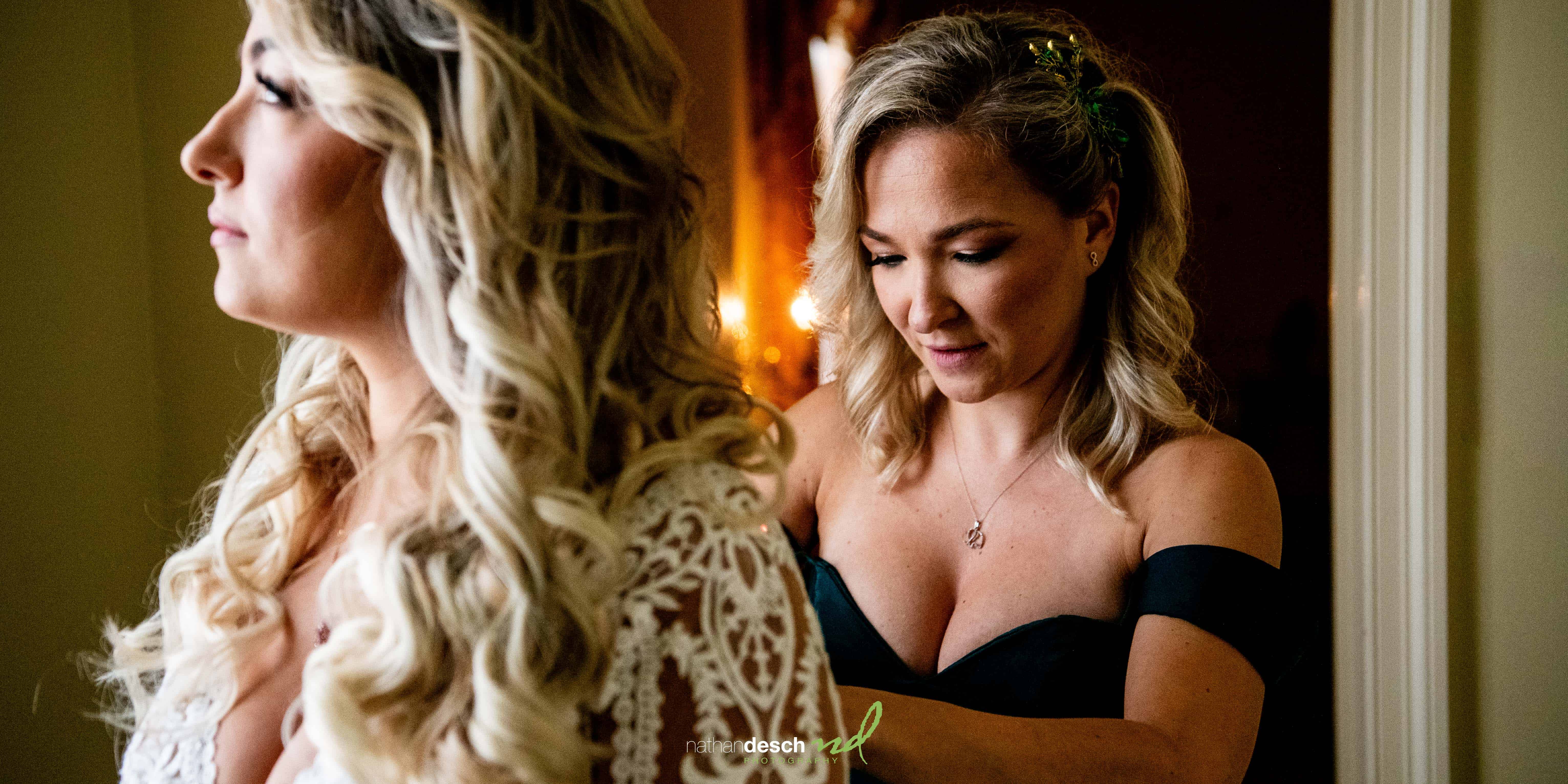 Sister helping bride get into dress