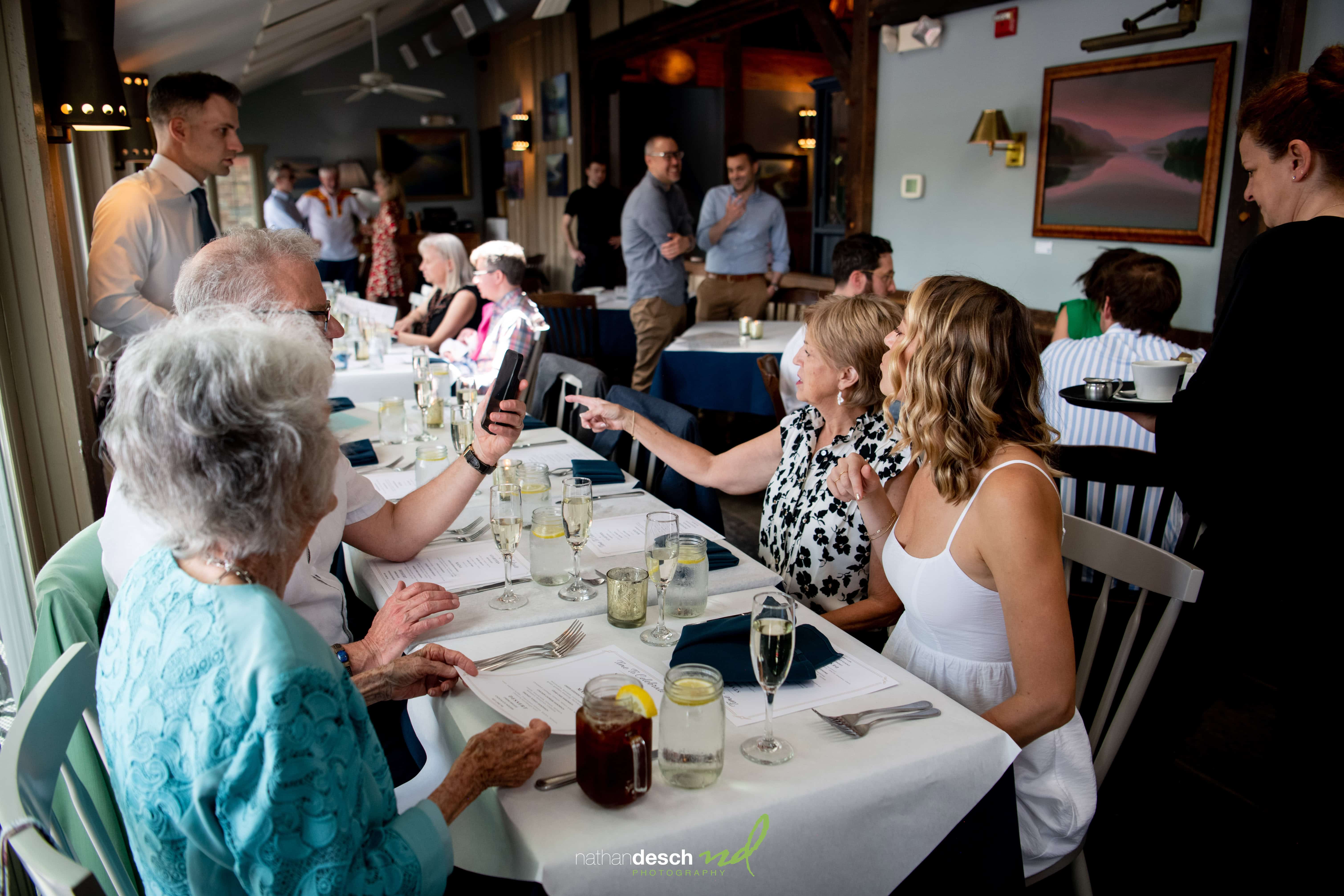 Bride and groom celebrate with friends at a wedding reception, gathered around an elegant restaurant dining table.