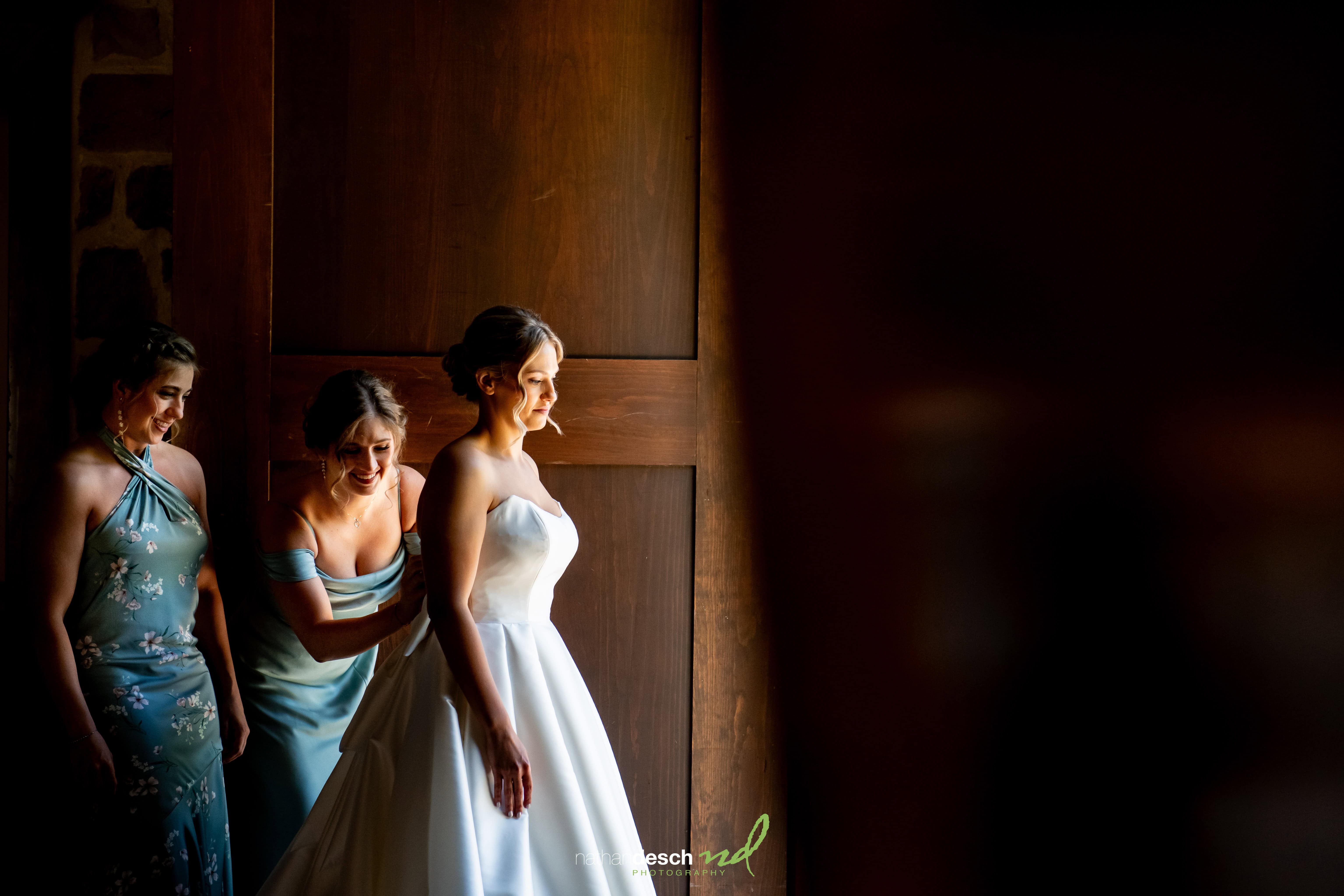 Bride in strapless white gown with bridesmaids in blue dresses getting ready at The Inn at Leola Village, spring wedding.