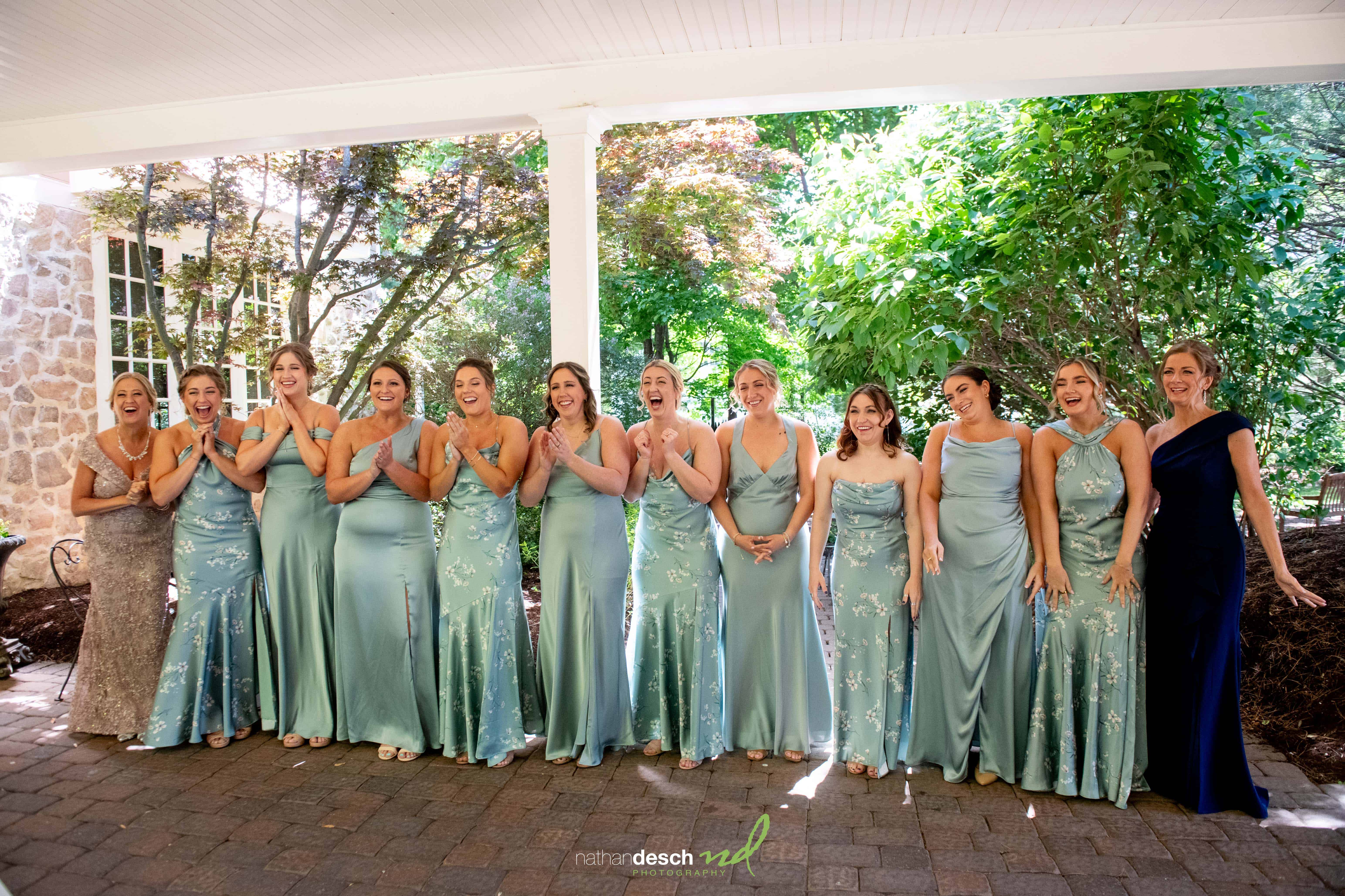 Bridesmaids in light blue and silver dresses pose joyfully at the Inn at Leola Village wedding under a covered outdoor patio.