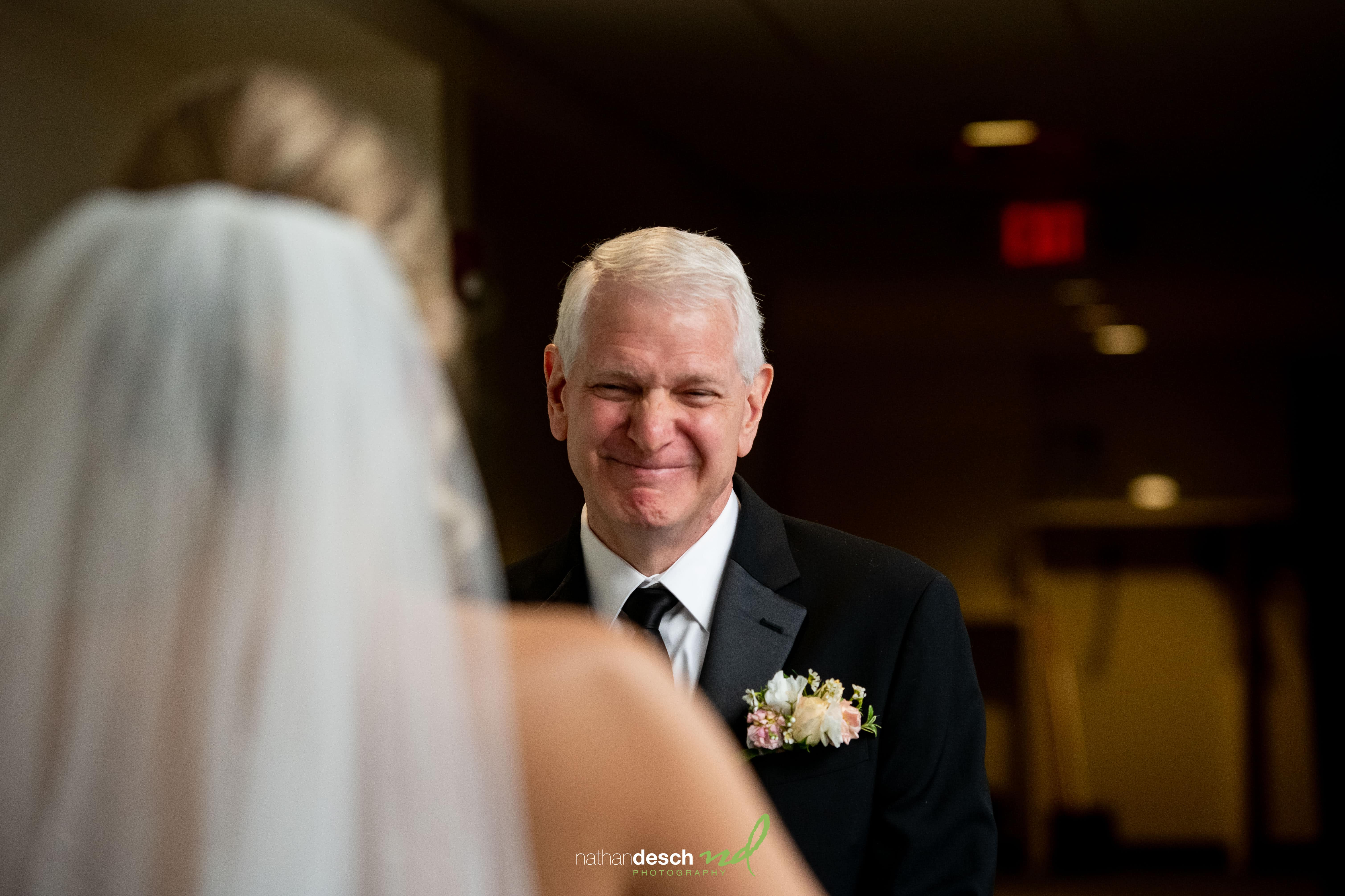 Groom in suit smiles at veiled bride during elegant wedding at The Inn at Leola Village, romantic dim lighting.