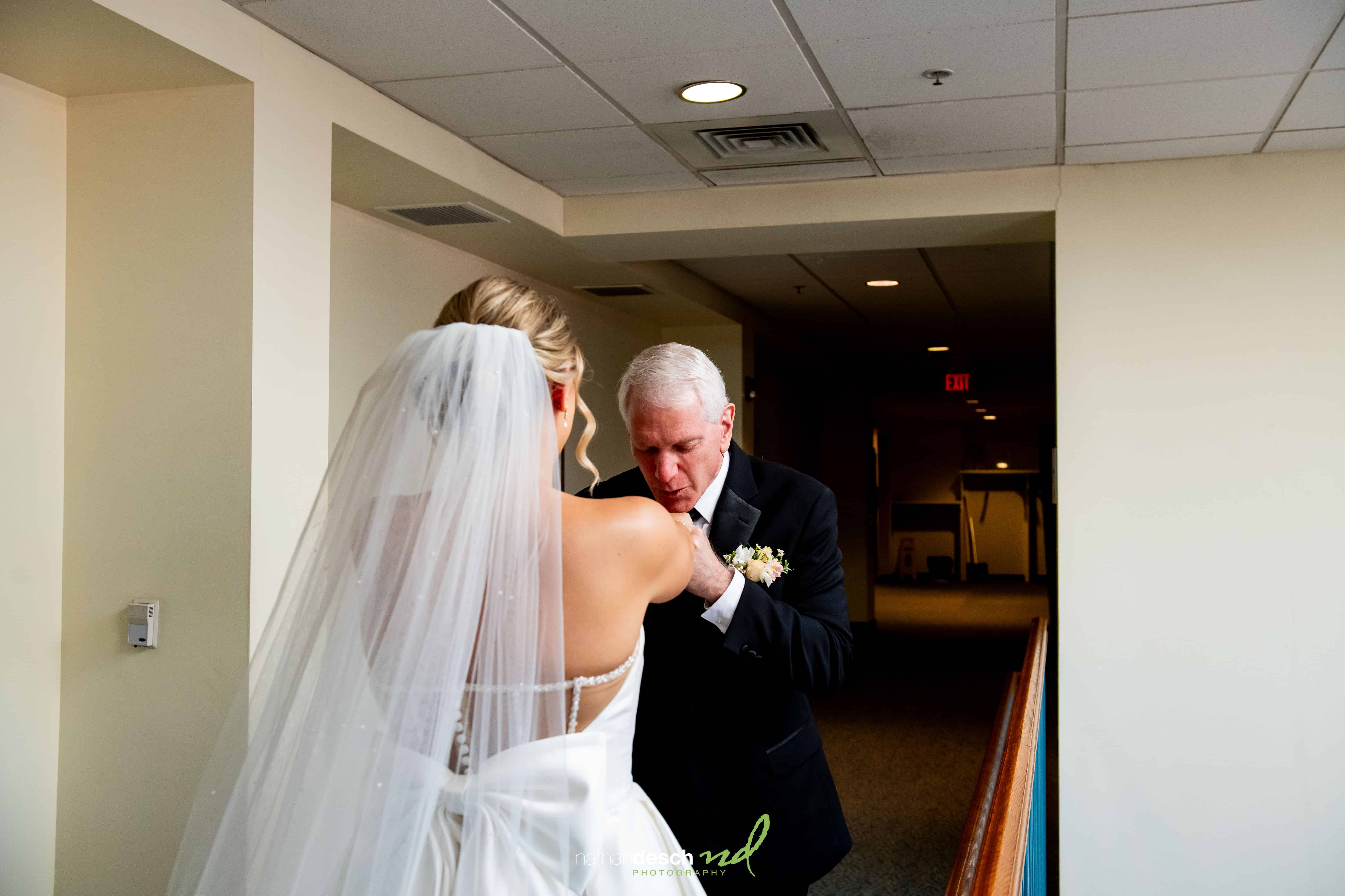 Bride in white dress and veil shares emotional pre-wedding moment as father kisses her hand at The Inn at Leola Village.
