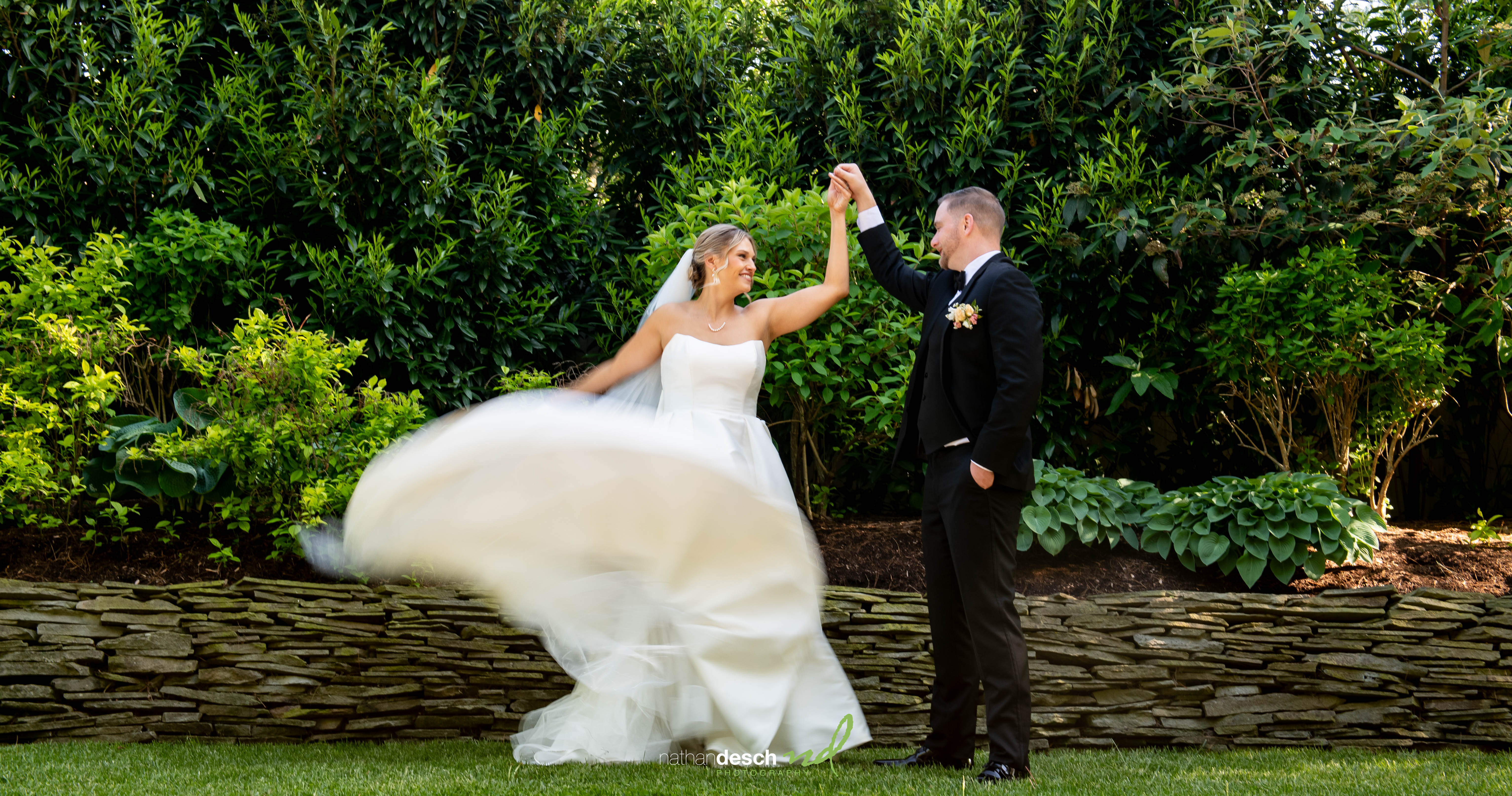 Bride and groom dancing outdoors at The Inn at Leola Village, surrounded by greenery, bride’s dress twirling gracefully.