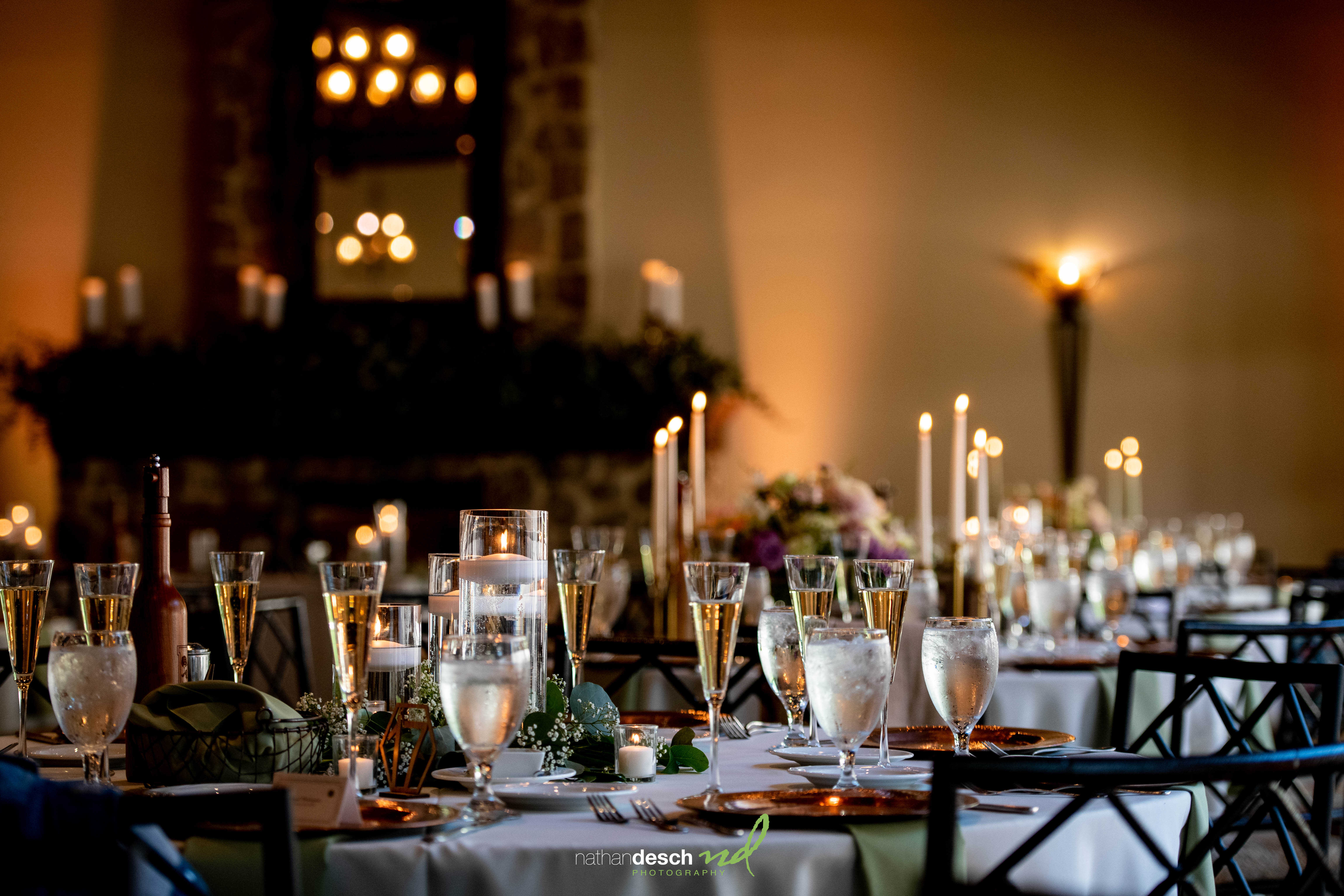 Elegant wedding banquet table at The Inn at Leola Village with champagne flutes, candles, floral centerpieces, and stone fireplace.
