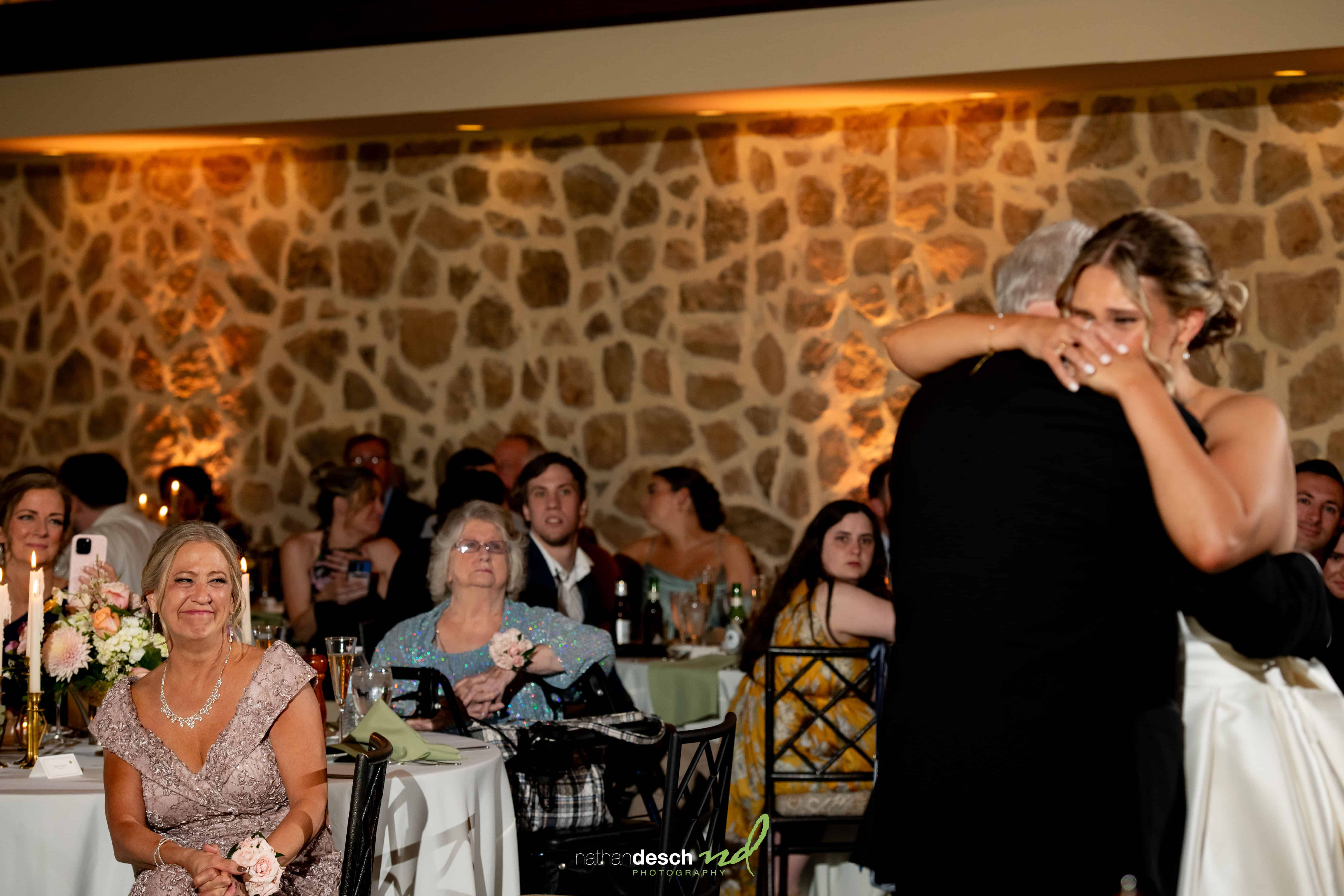 Bride sharing emotional dance with father at Inn at Leola Village wedding, guests smiling in warmly lit stone-walled venue.