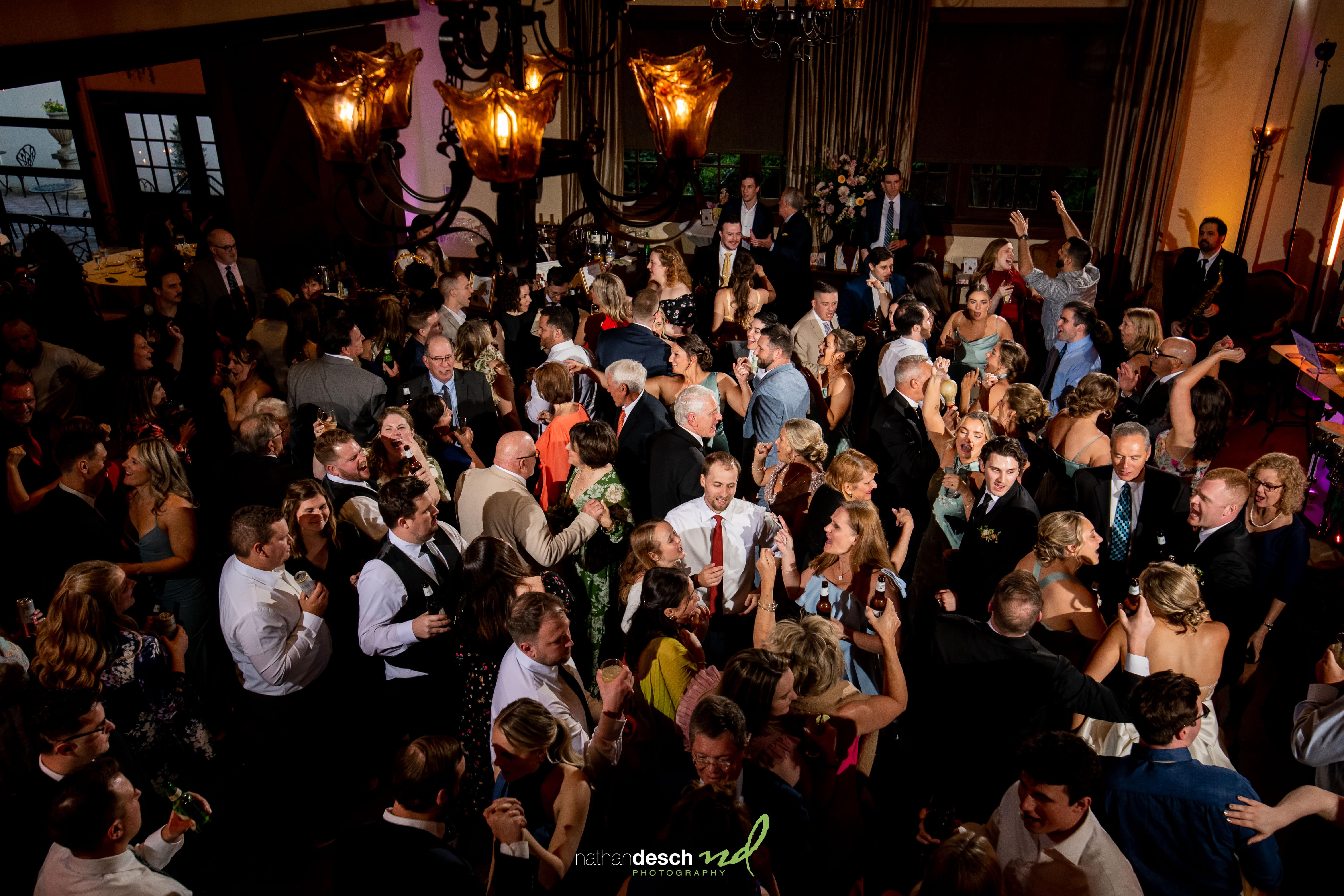 Guests in formal attire dancing and celebrating under chandeliers at an elegant Inn at Leola Village wedding reception.