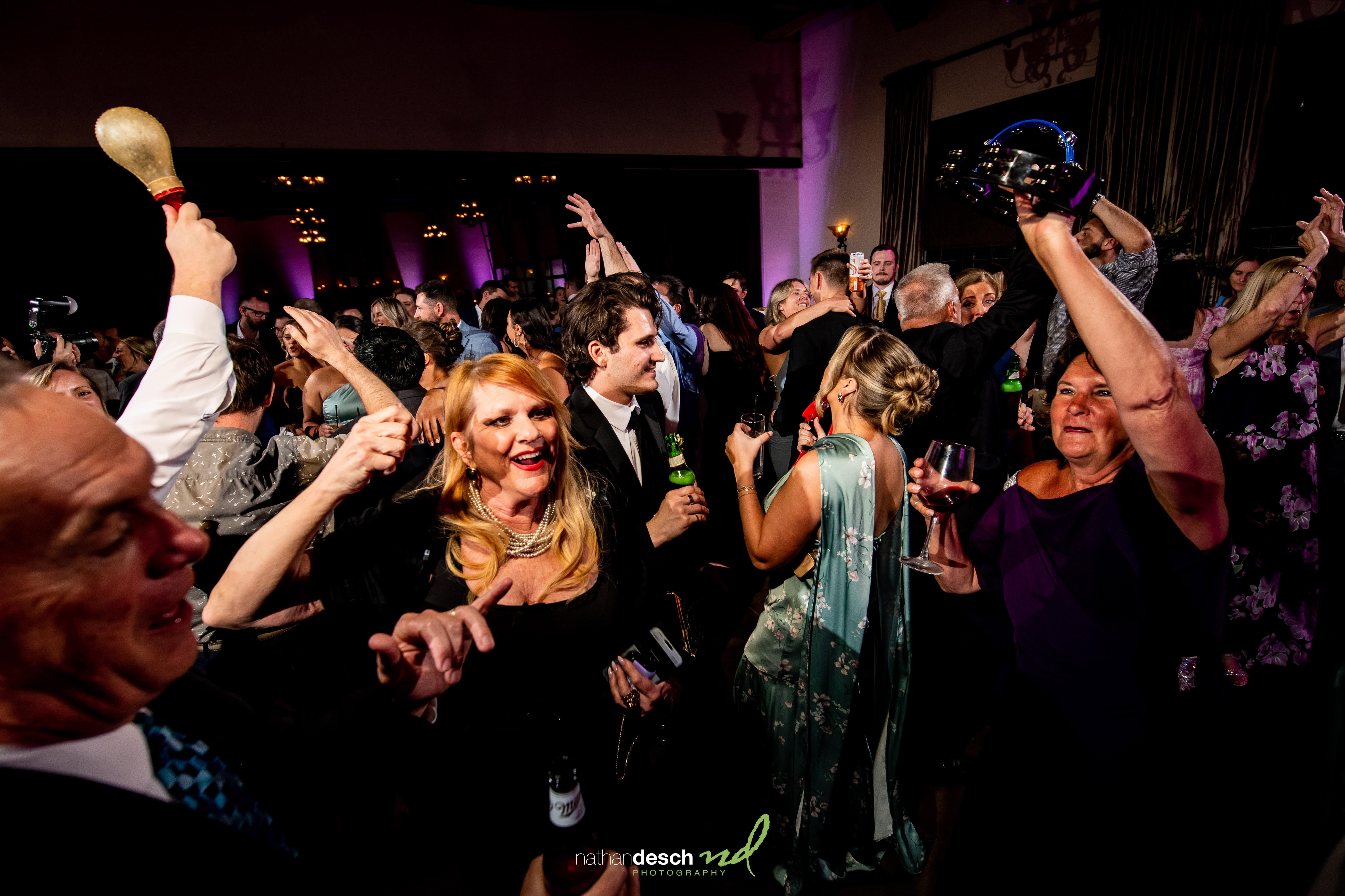 Guests in formal attire dance and celebrate with maracas at a festive wedding reception at the Inn at Leola Village.