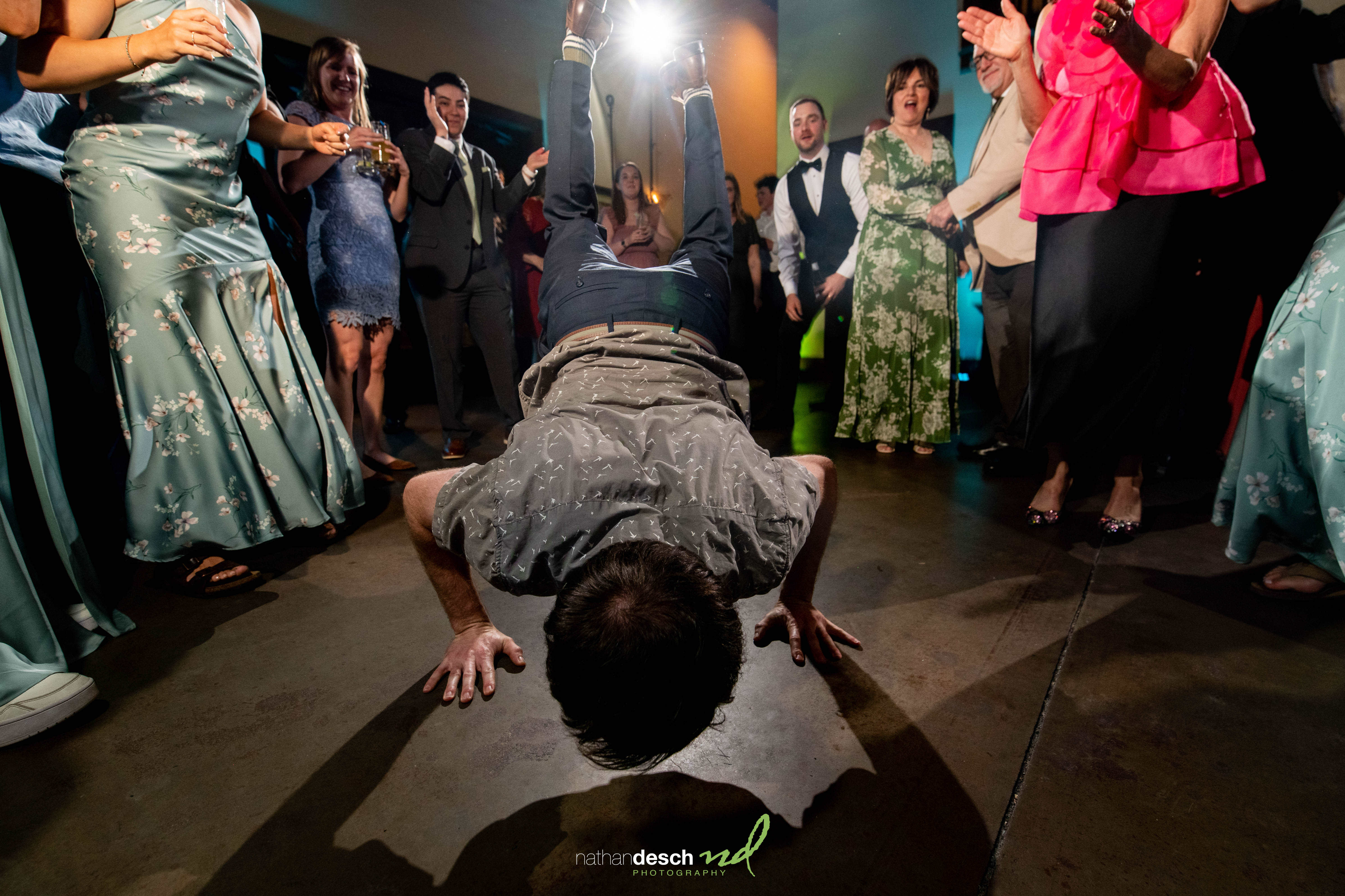 Groom breakdancing surrounded by cheering guests in formal attire at bright, elegant Inn at Leola Village wedding reception.