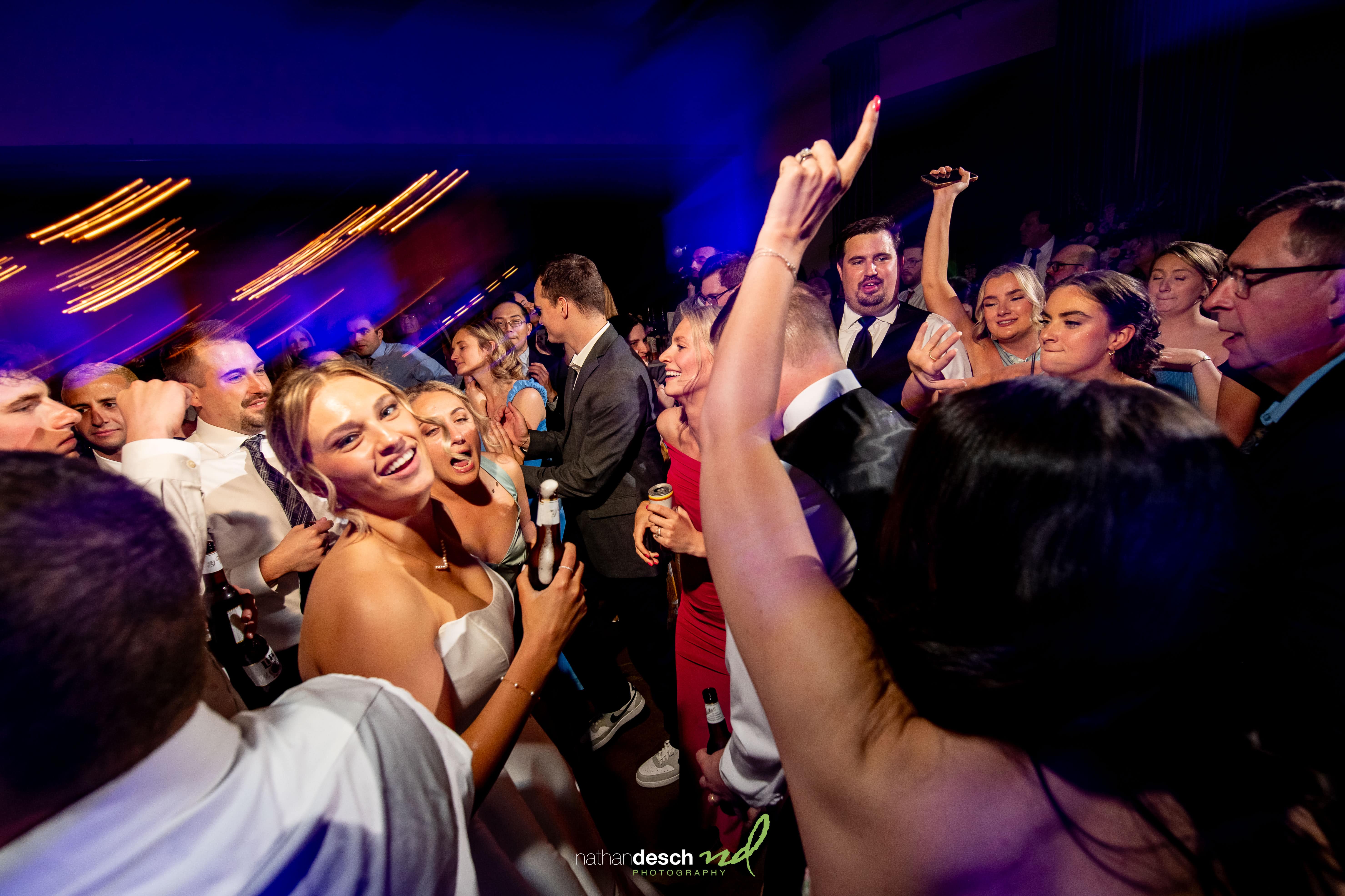 Guests dancing and celebrating at an elegant Inn at Leola Village wedding reception under vibrant, colorful lights.