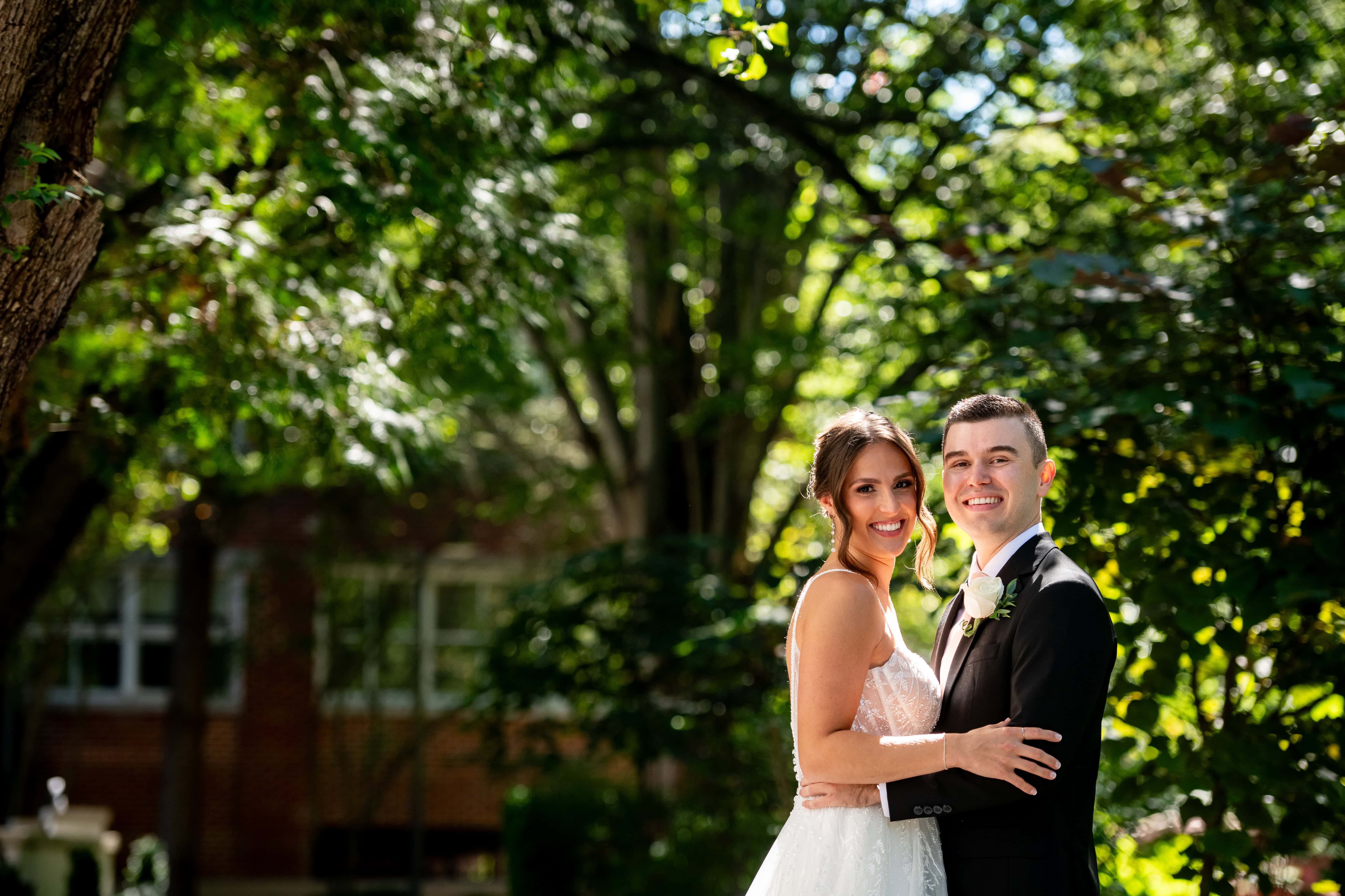 Bride and groom smiling together in sunlit greenery at River House at Odettes wedding, perfect romantic moment.