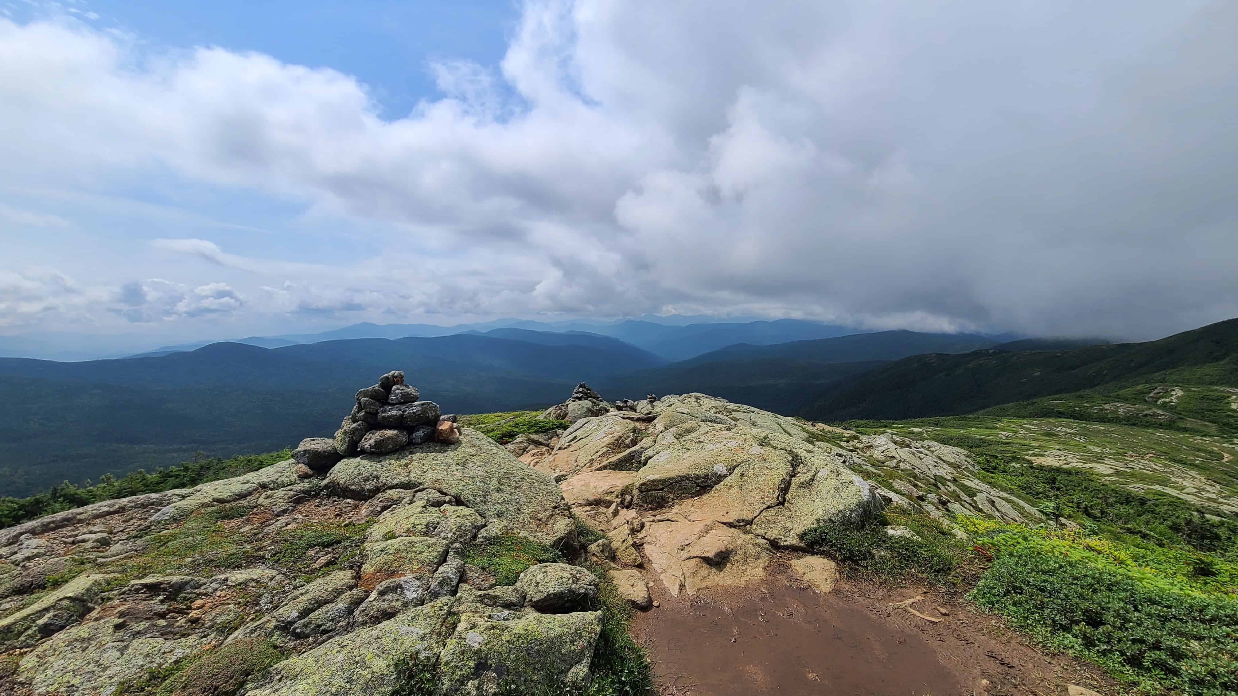 White Mountains summit with stone cairns, green hills, blue peaks—perfect backdrop for adventure elopement wedding photos.
