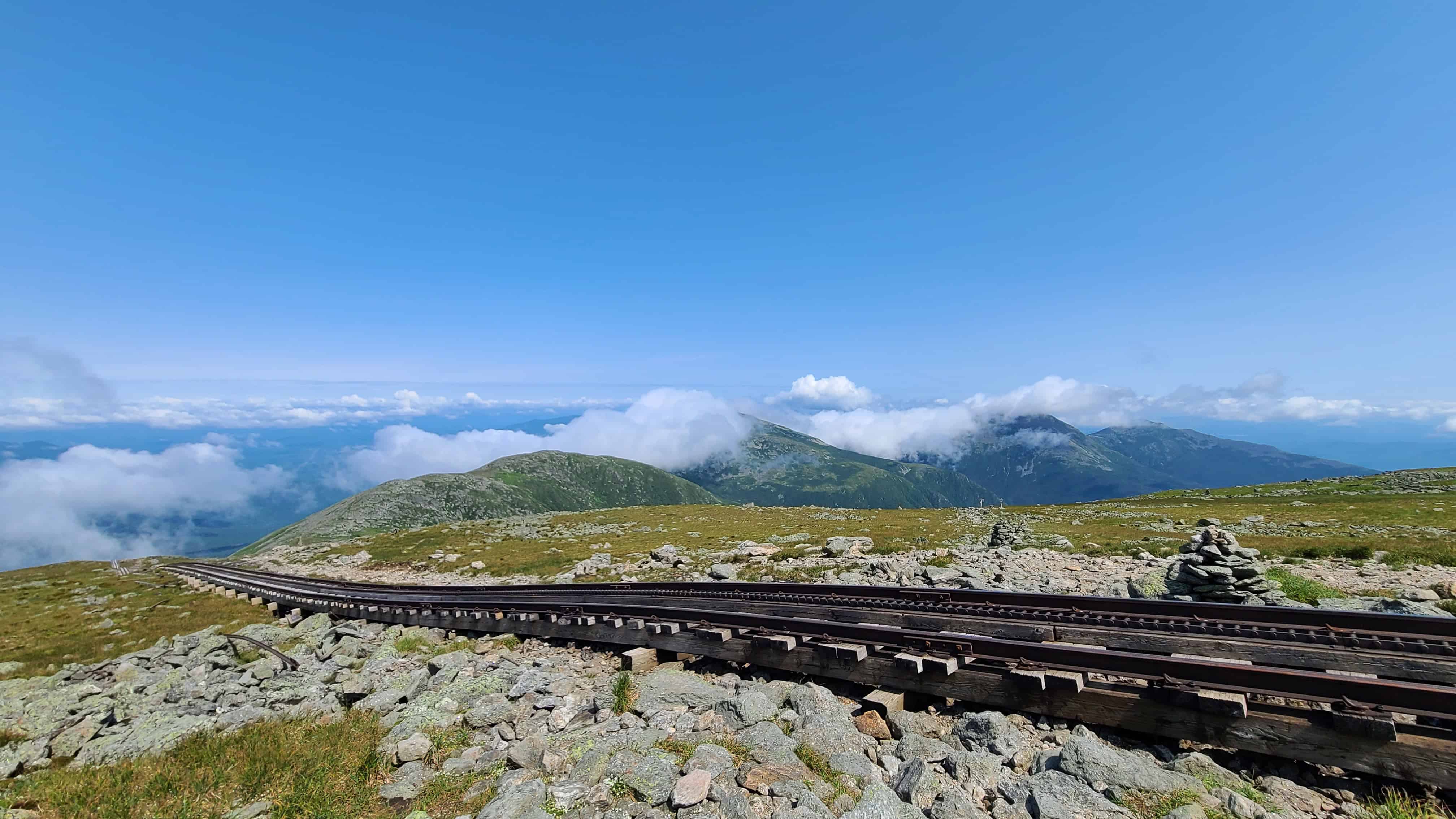 White Mountains wedding scene with rocky terrain, grassy patches, railway track, blue sky, ideal for adventurous elopements.
