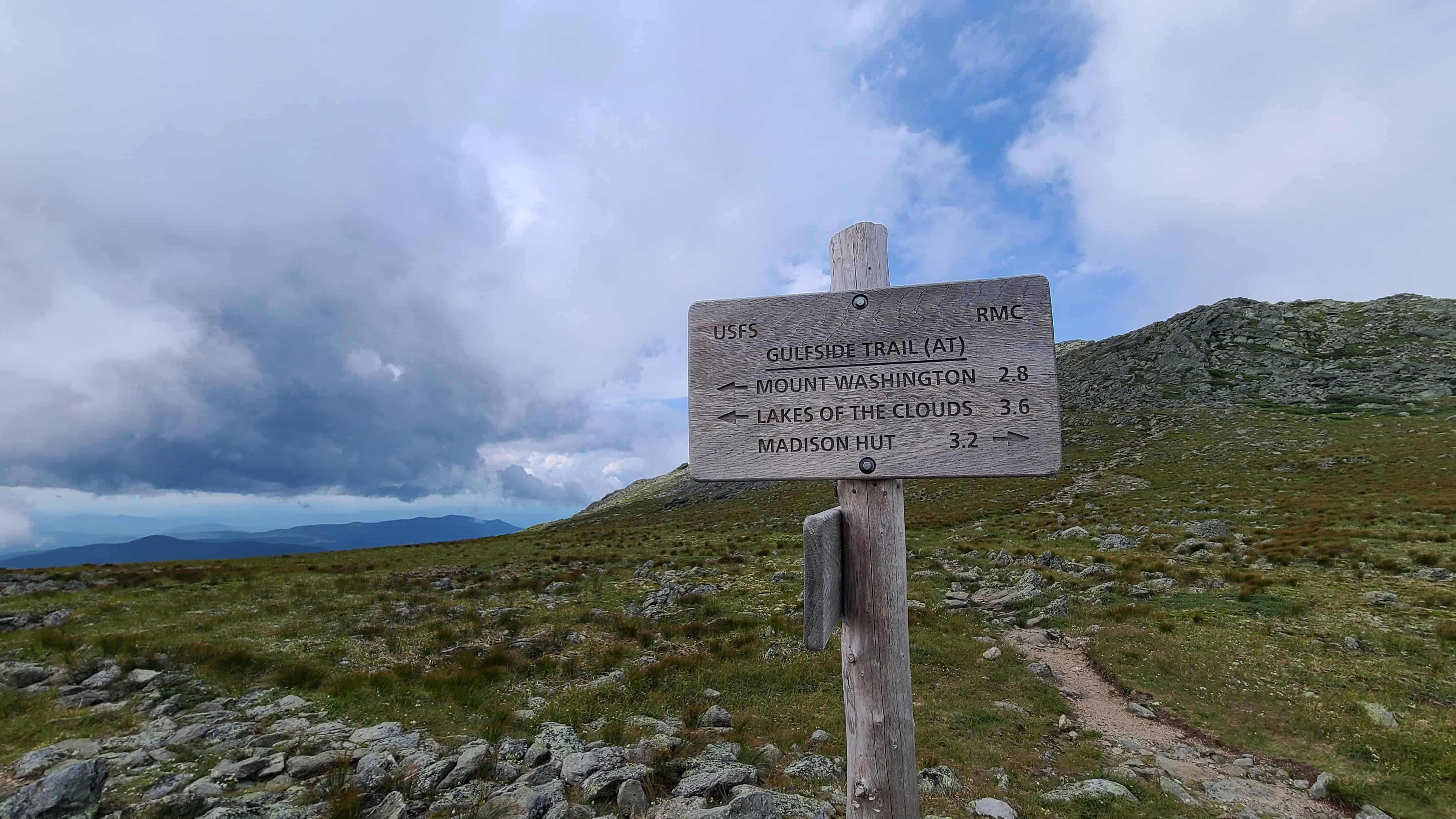 Wooden trail sign in White Mountains with cloudy sky, ideal adventure wedding or elopement spot near Mount Washington.