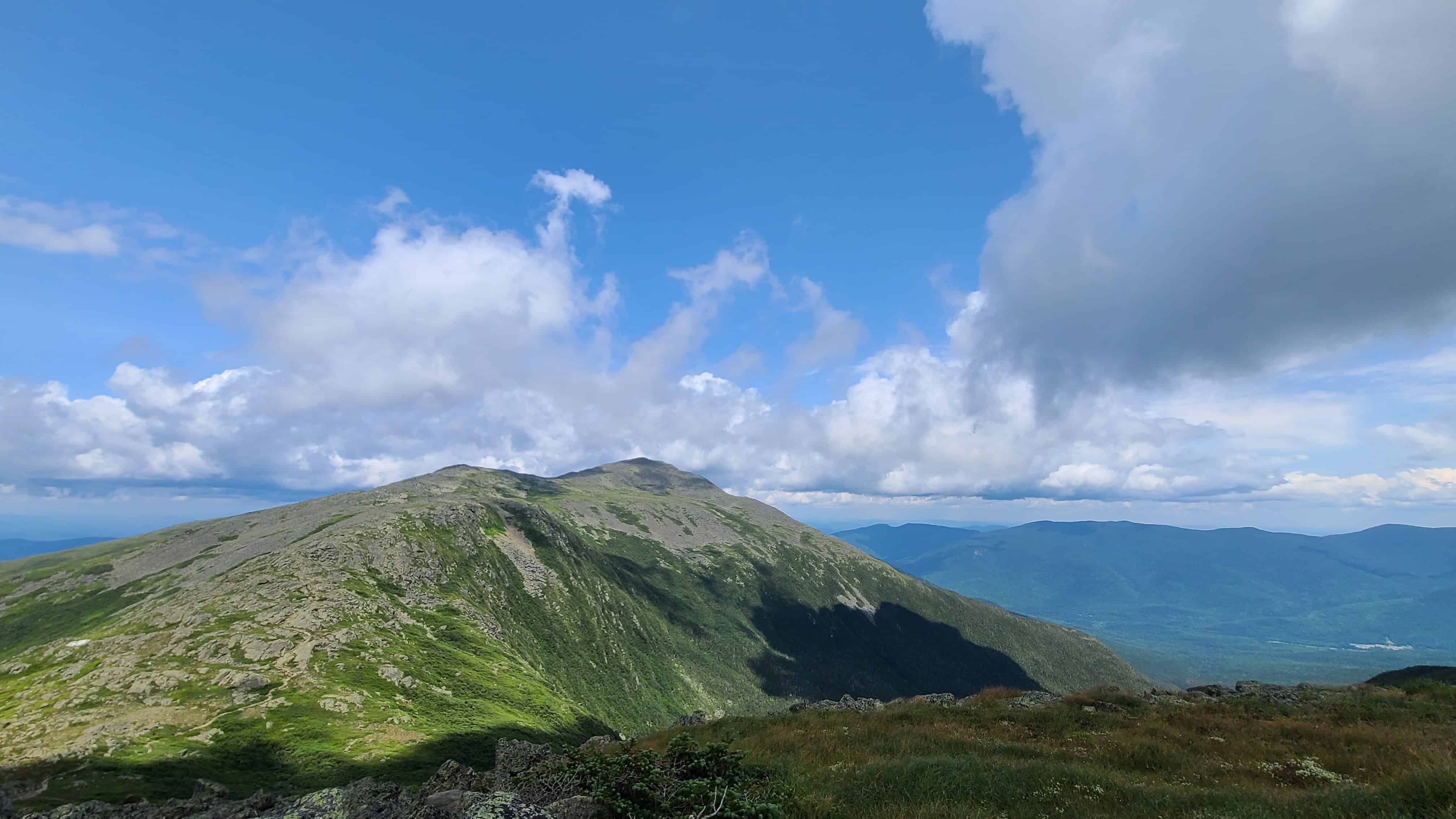 Stunning White Mountains view with lush green slopes and blue sky, ideal outdoor backdrop for an adventure wedding.