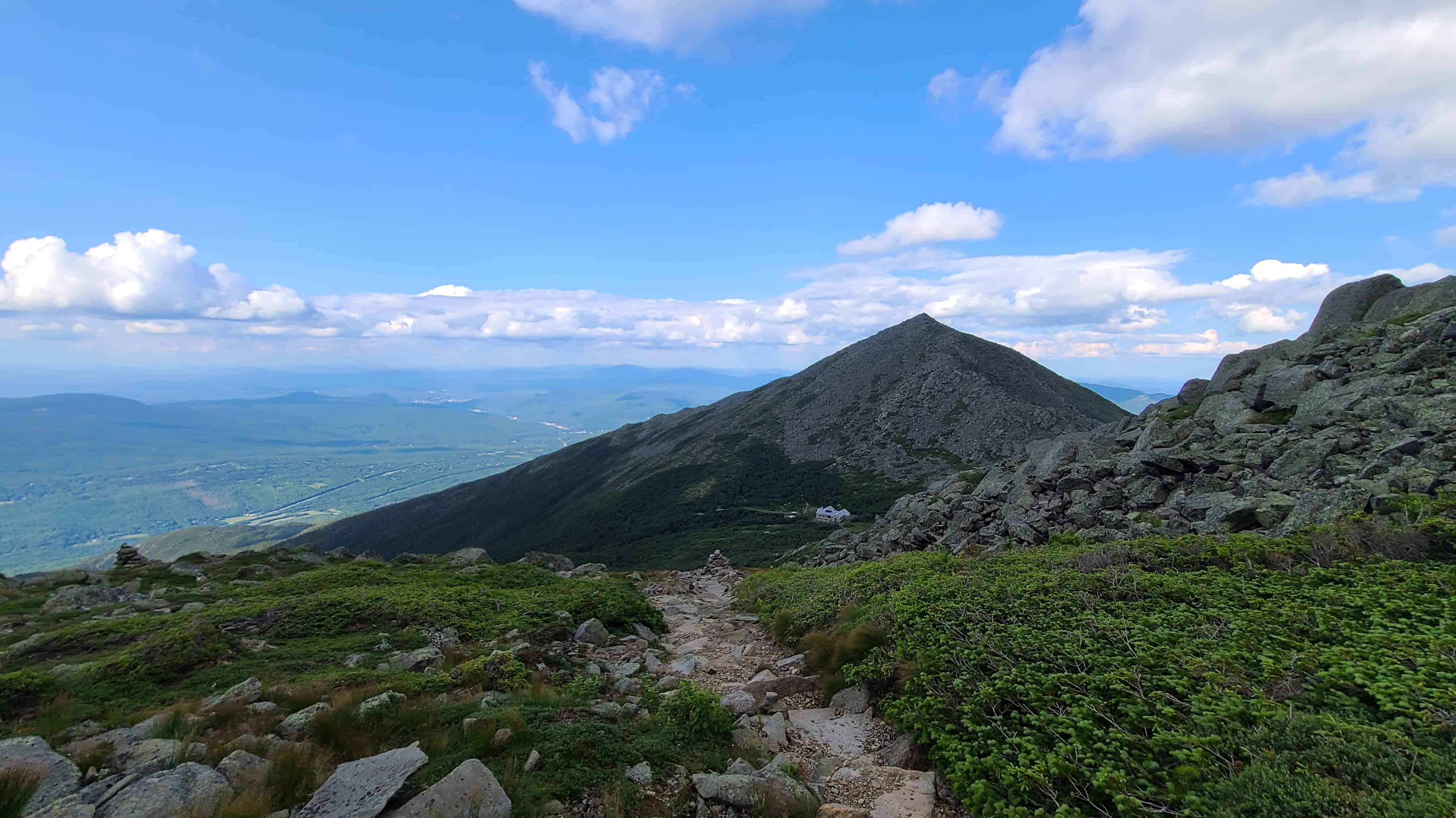Rocky trail with green shrubs and mountain views, ideal for adventure elopement photos in the scenic White Mountains.