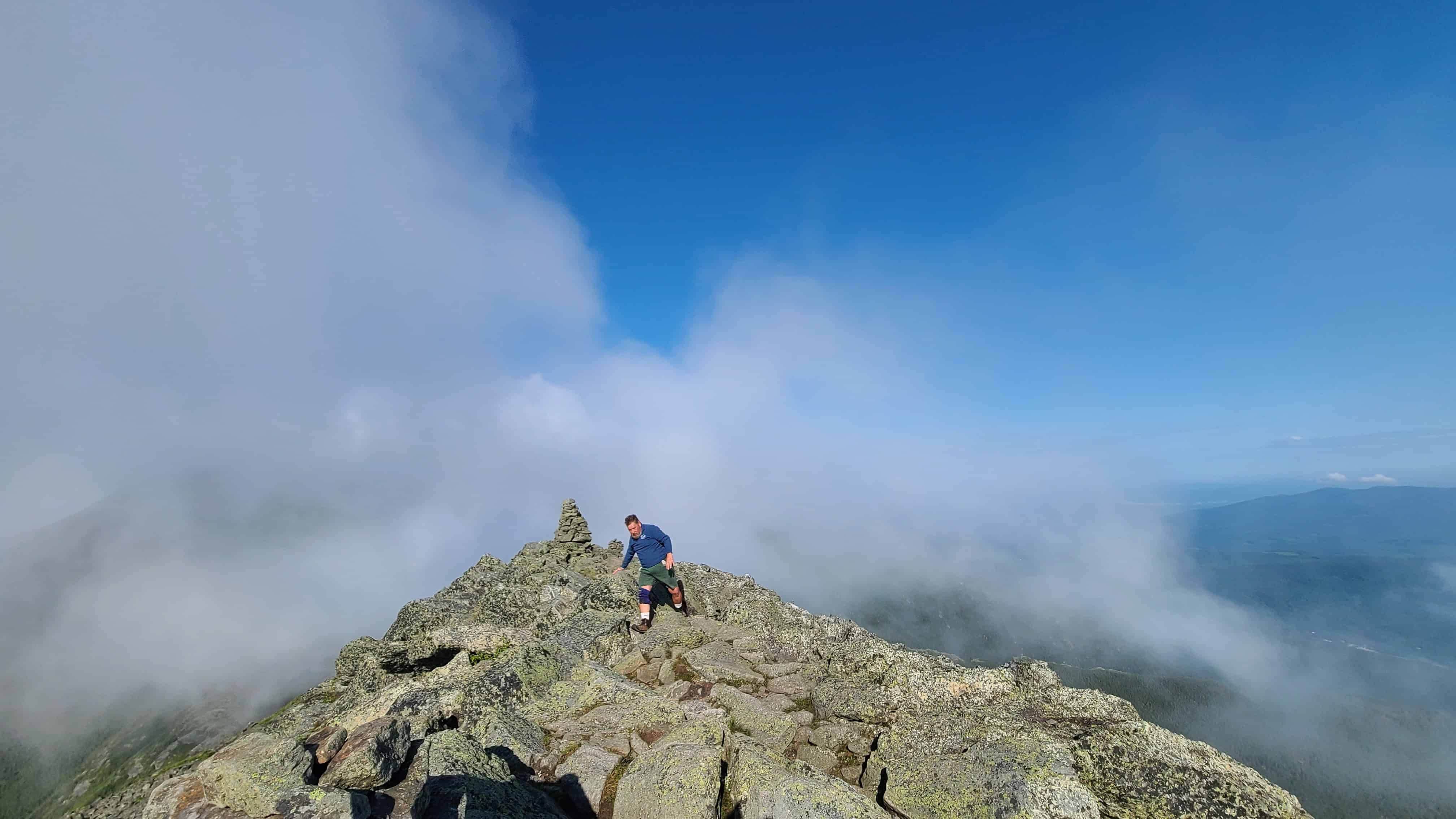 Adventurous couple hikes rocky ridge in the White Mountains, surrounded by clouds—ideal for an elopement or wedding shoot.