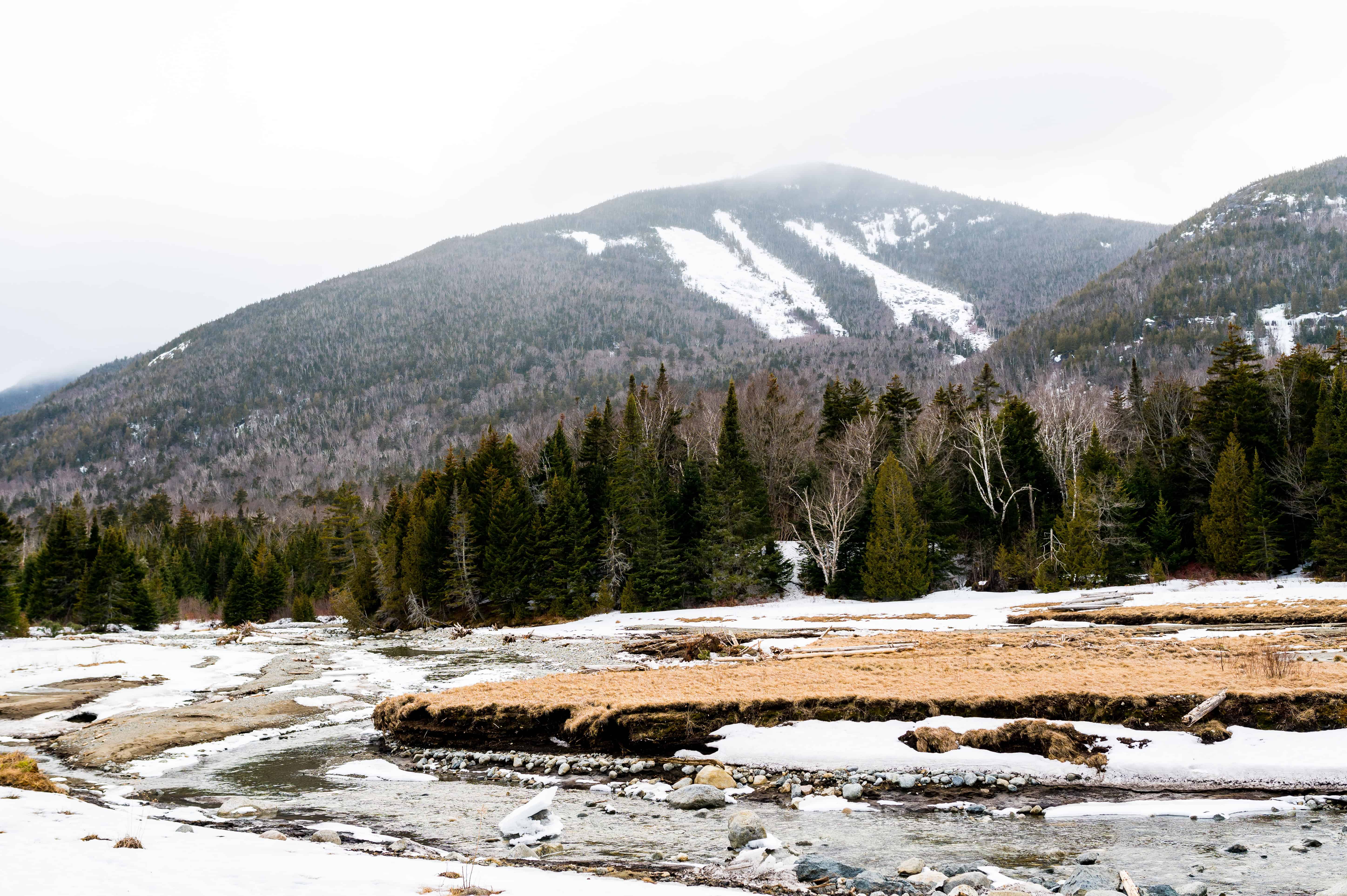 Snowy White Mountains with ski trails, evergreens, and a frozen river—perfect backdrop for an adventure wedding photo.