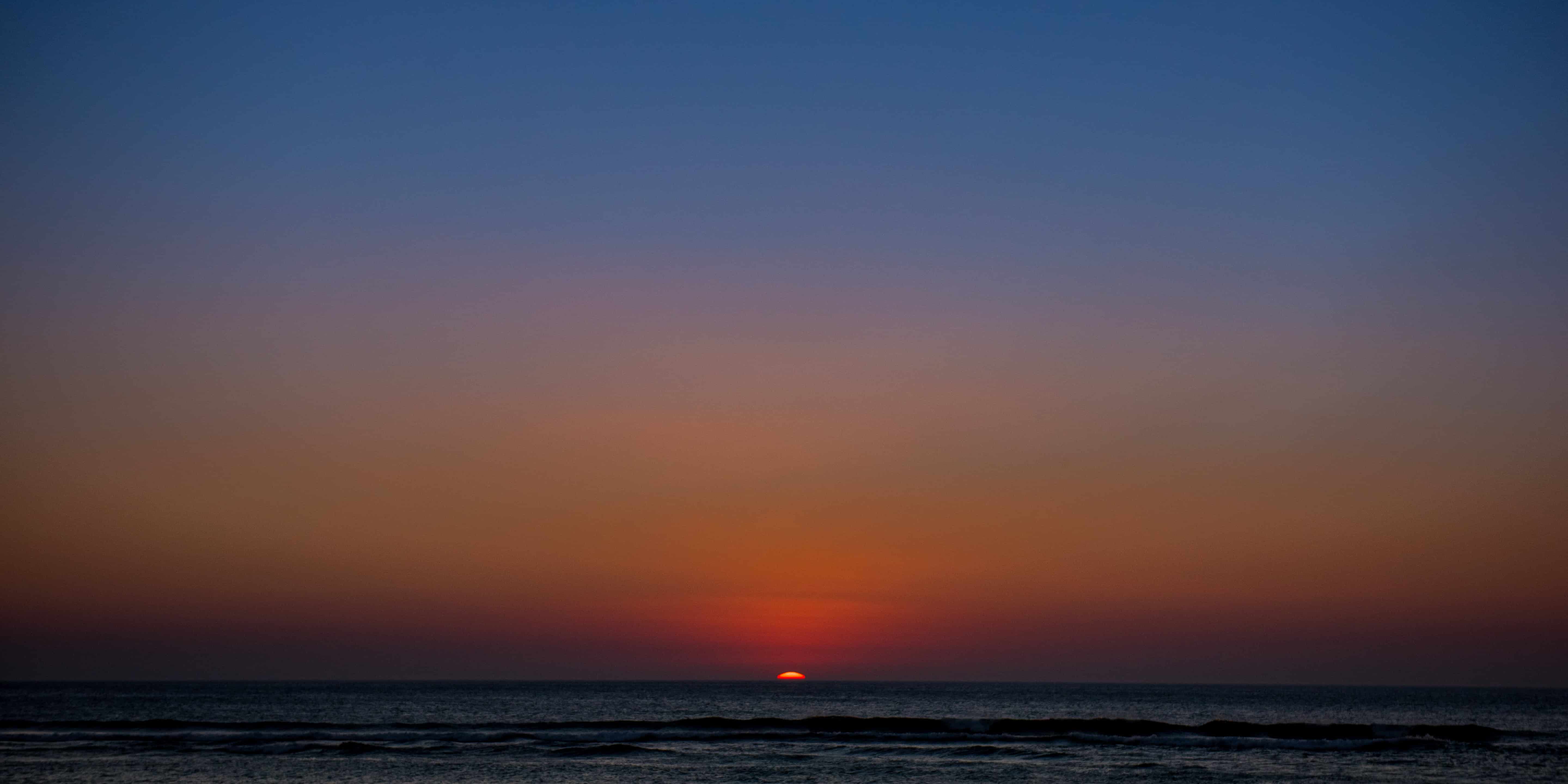 Romantic ocean sunset with vibrant orange, red, and purple sky—perfect backdrop for wedding photography sessions.