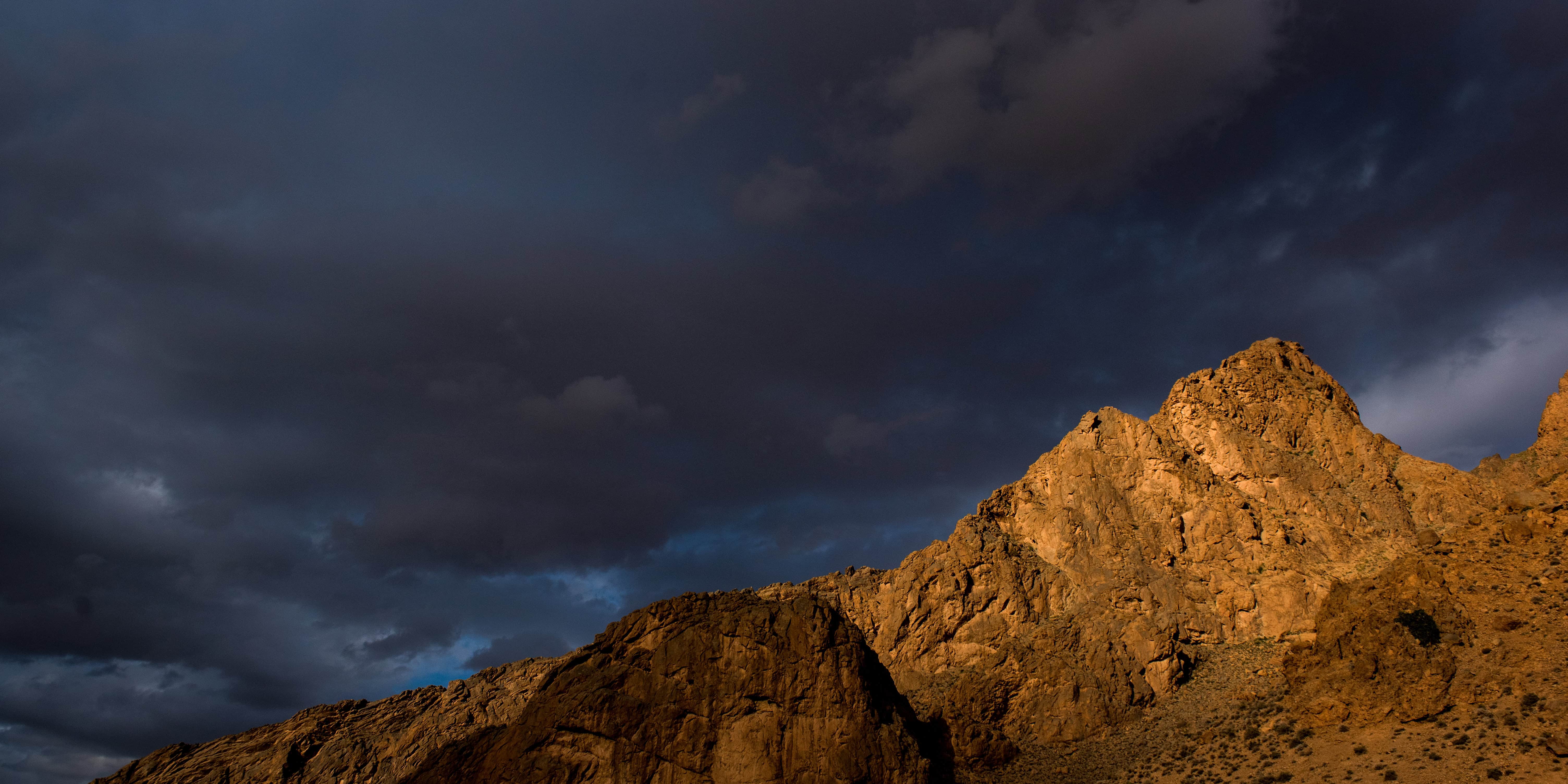 Golden desert rocks beneath a stormy sky in the Sahara—ideal backdrop for Marrakech or Morocco elopement photography.