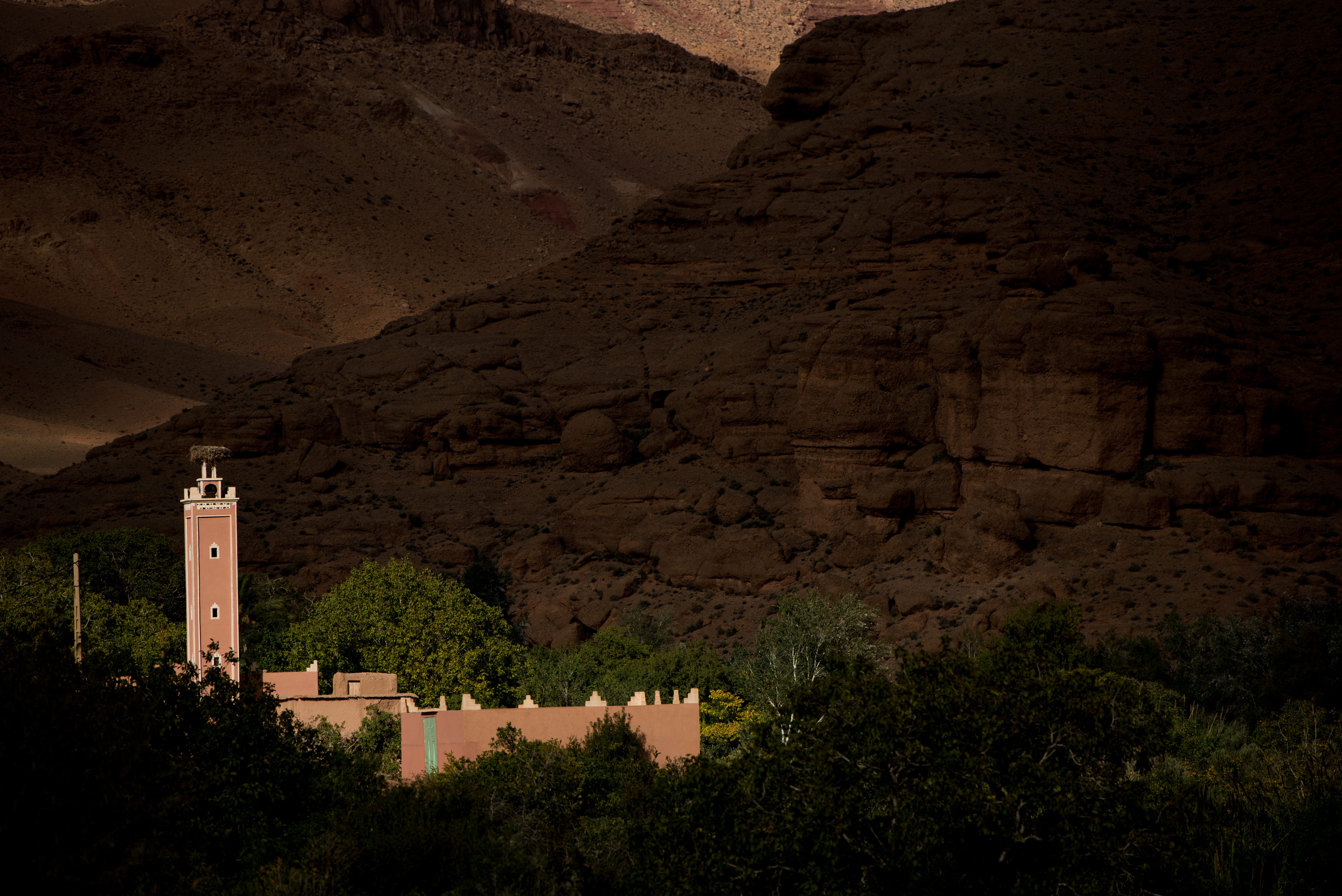 Pink minaret with stork nest near Marrakech, dramatic cliffs, perfect romantic Morocco elopement photography scenery.