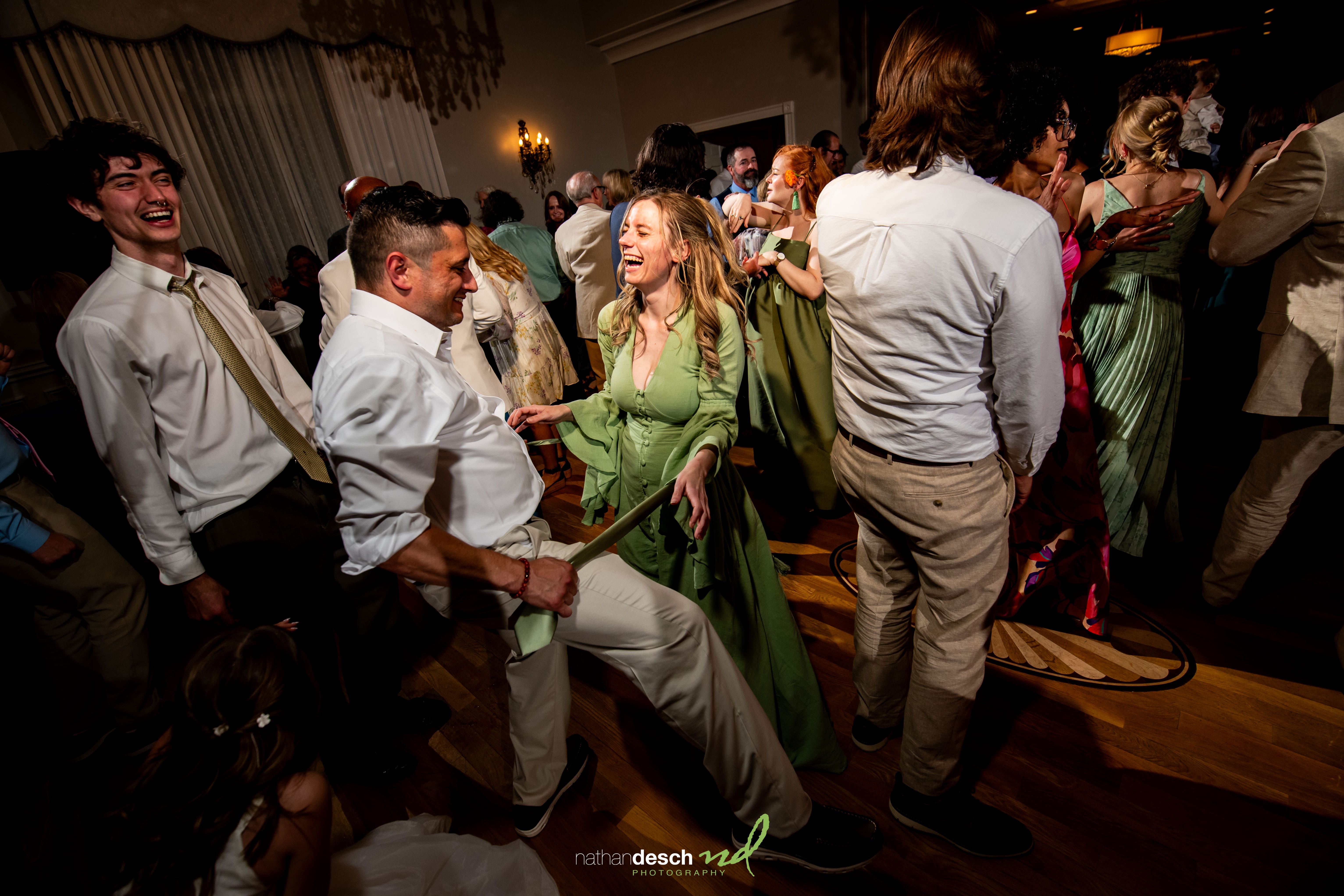 Garrett and Ashley dance and laugh at a joyful University and Whist Club wedding, surrounded by guests in formal attire.