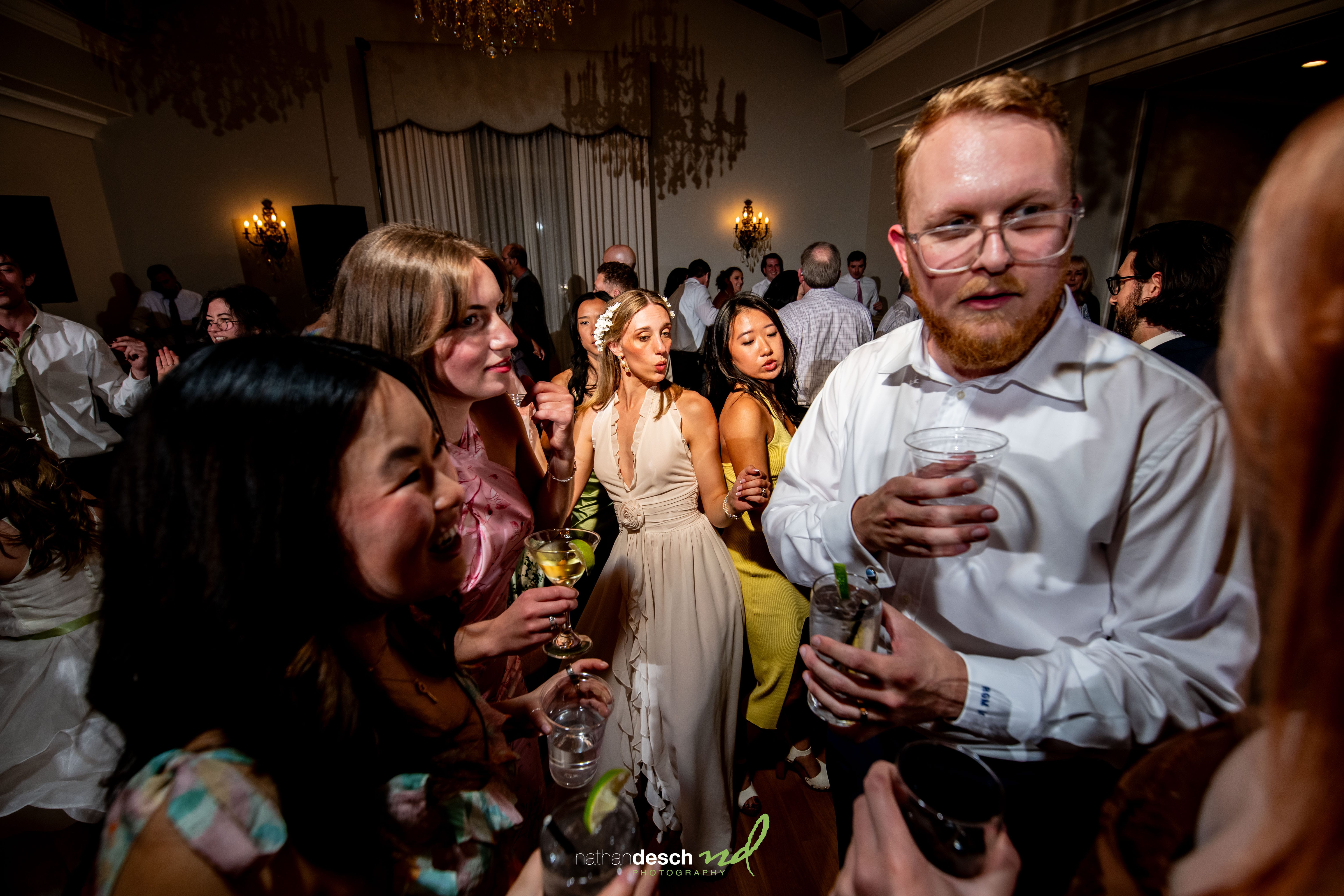 Elegant wedding guests socialize with drinks at Garrett and Ashley’s University and Whist Club reception, lively indoor celebration.