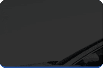 A dark, minimalistic image showing the top corner of a car’s windshield and roof against a plain dark background.