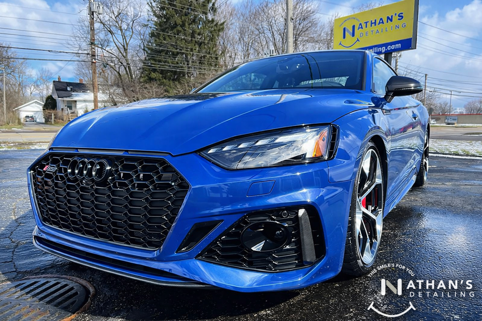 Front angle view of a blue Audi with a high-gloss ceramic coating finish parked outside Nathan's Detailing.