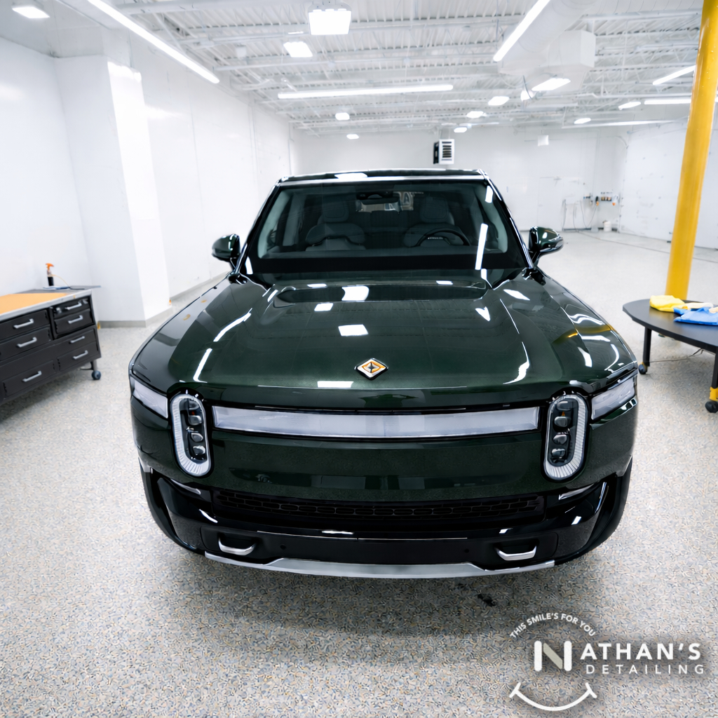 A forest green Rivian R1T electric truck in a clean detailing studio, illustrating the sleek look of a protected vehicle.