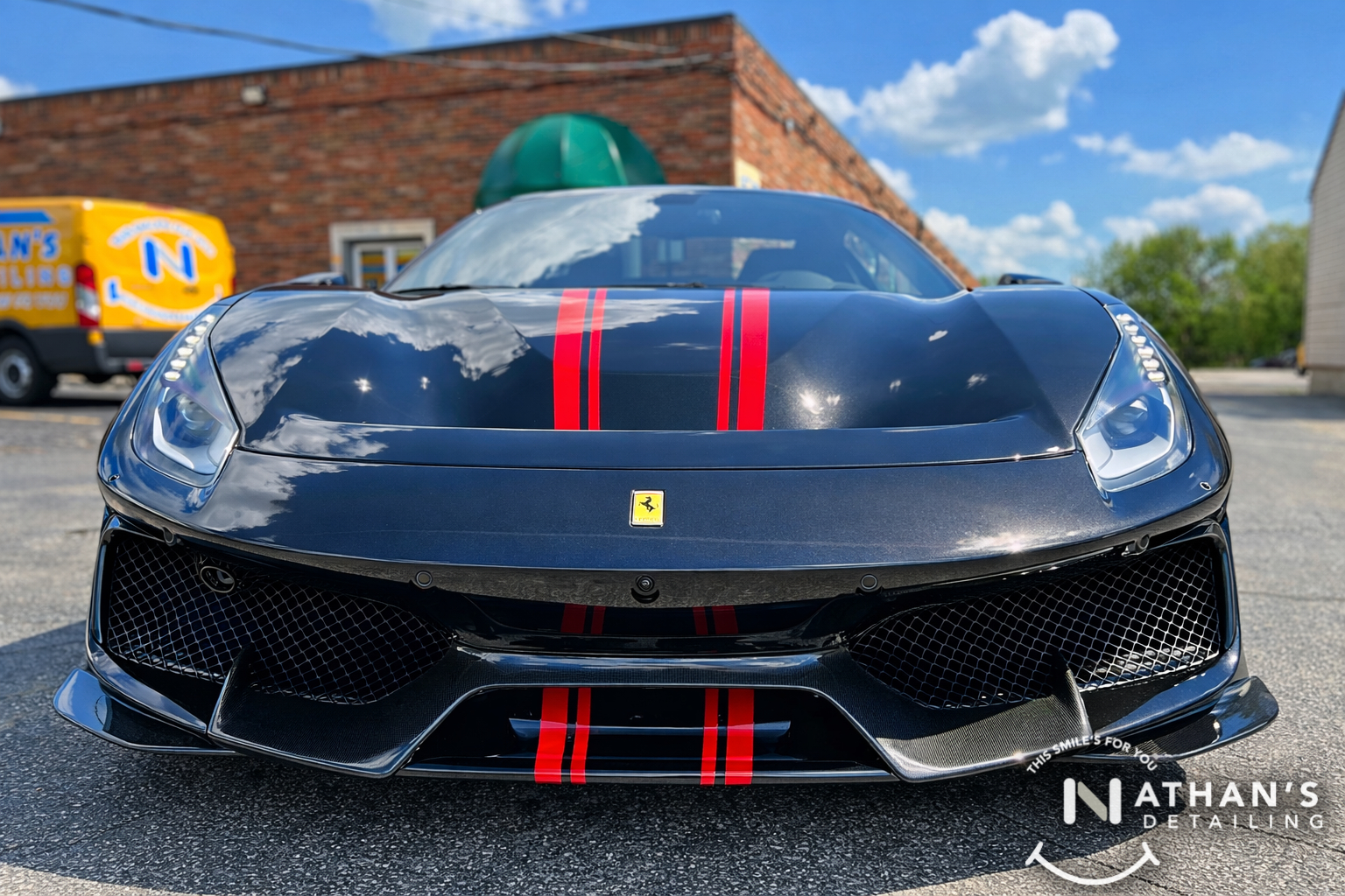 A black Ferrari with red racing stripes is parked outside on pavement under a blue sky. The front of the car is shown, and a Nathans Detailing logo appears in the bottom right corner.