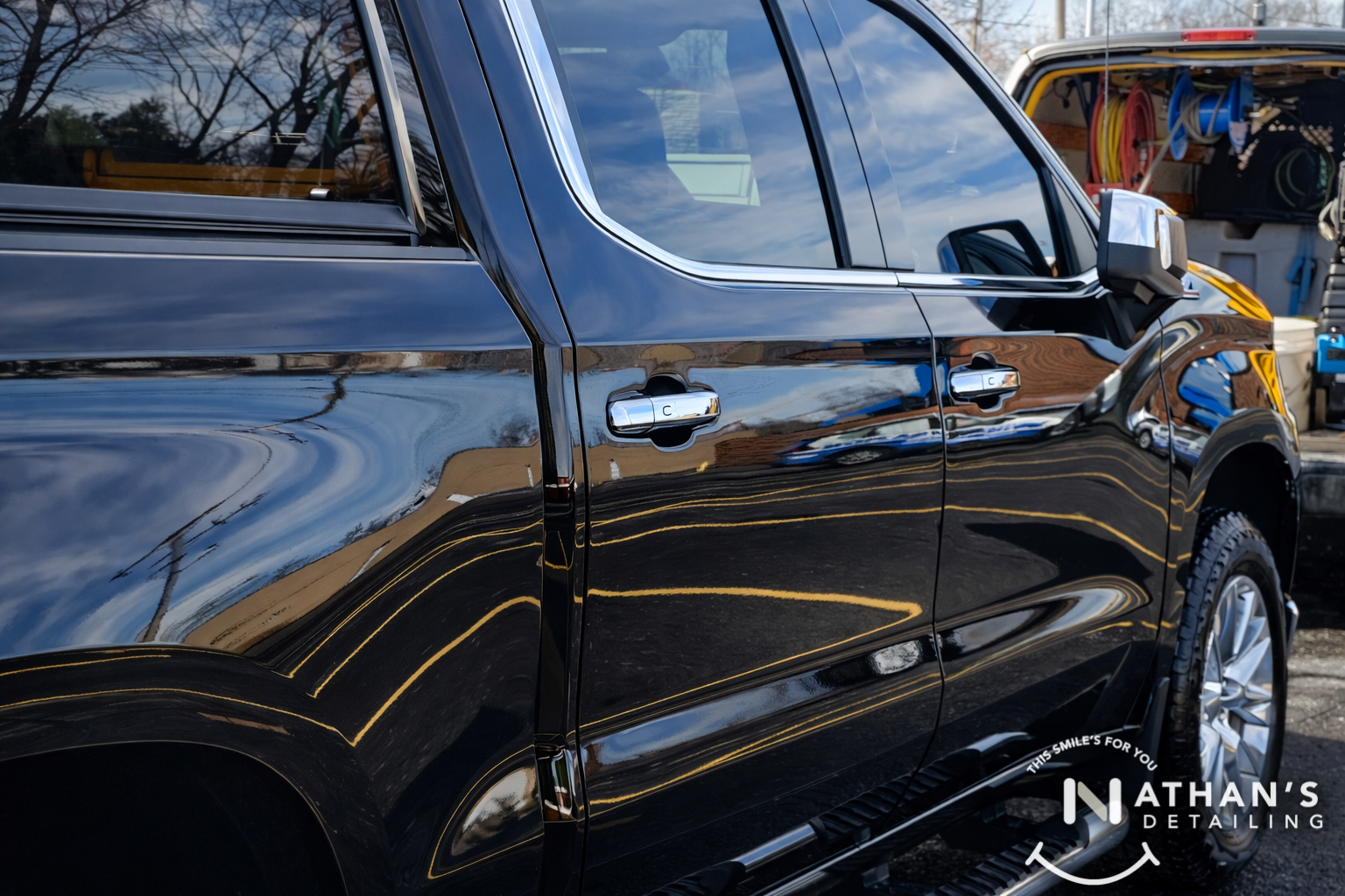 Glossy black truck door reflection during mobile detailing
