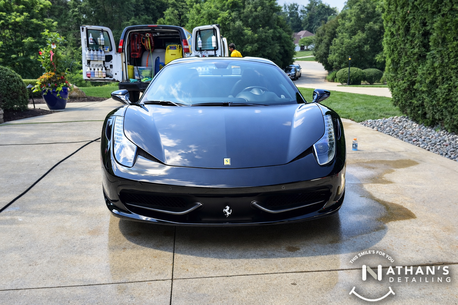 Mobile detailing setup behind black ferrari